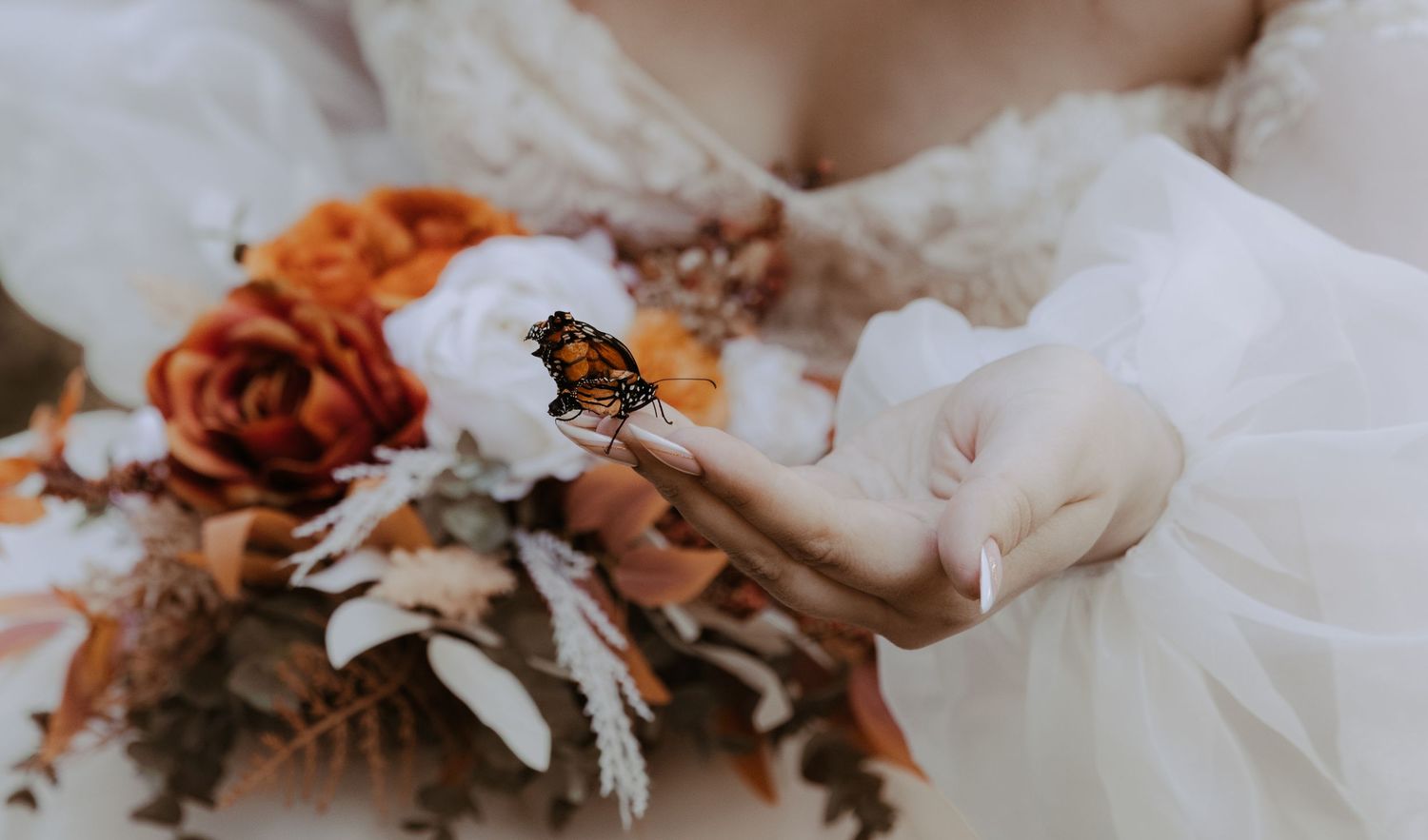 Close-up of orange and white bridal bouquet with butterfly detail.