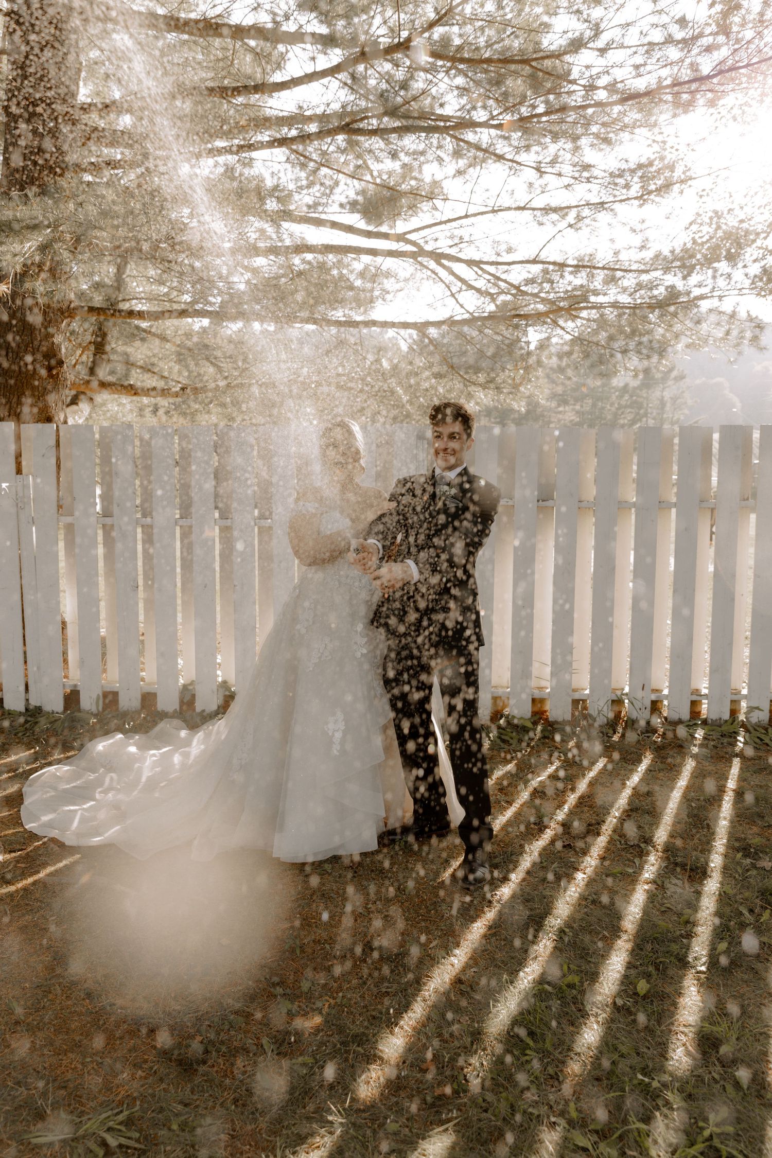 A romantic wedding photo with snow-like particles dancing in golden sunlight.