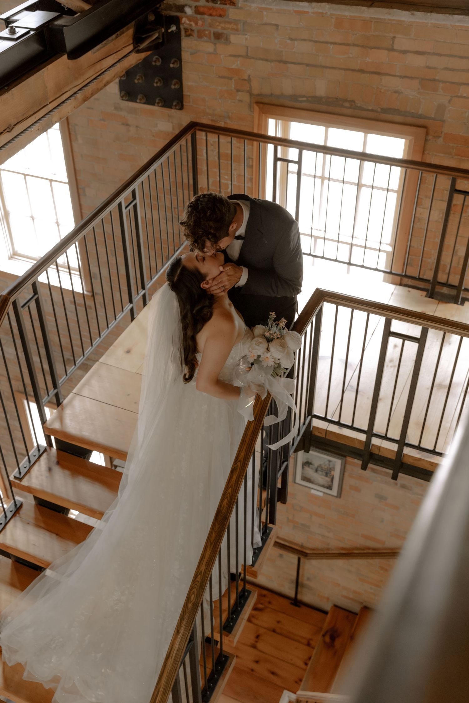 Artistic overhead view of wedding couple sharing intimate moment on wooden staircase.