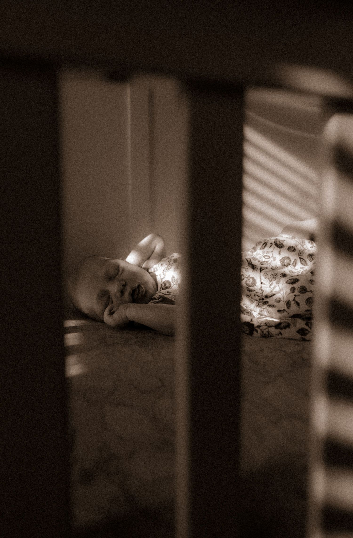 Sunlight streaming through crib slats creates dramatic shadows in a peaceful nursery scene.