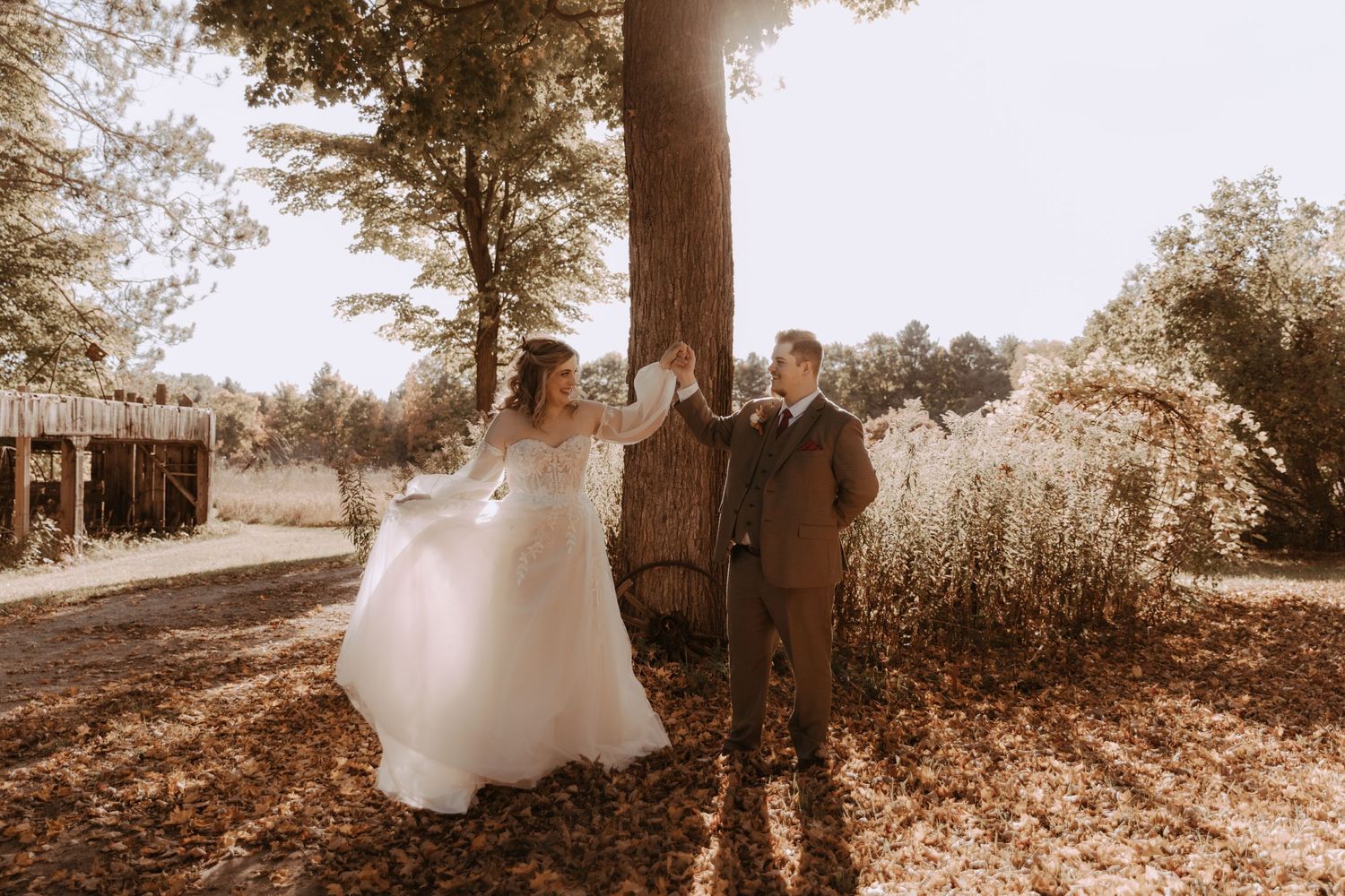 Joyful wedding moment captured in sepia tones under autumn trees.