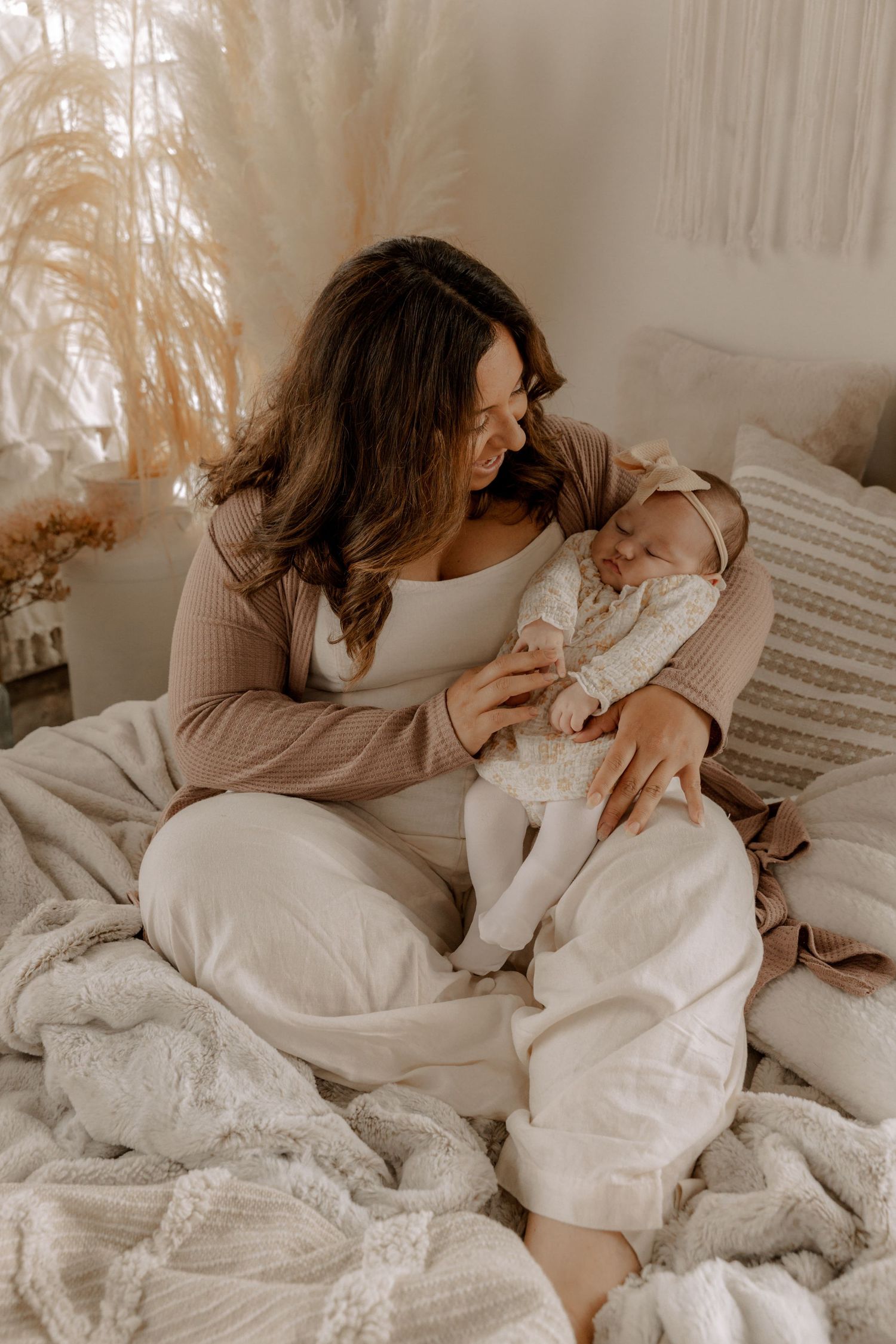 Peaceful morning scene of parent and baby cuddling together on white bedding in warm natural light.