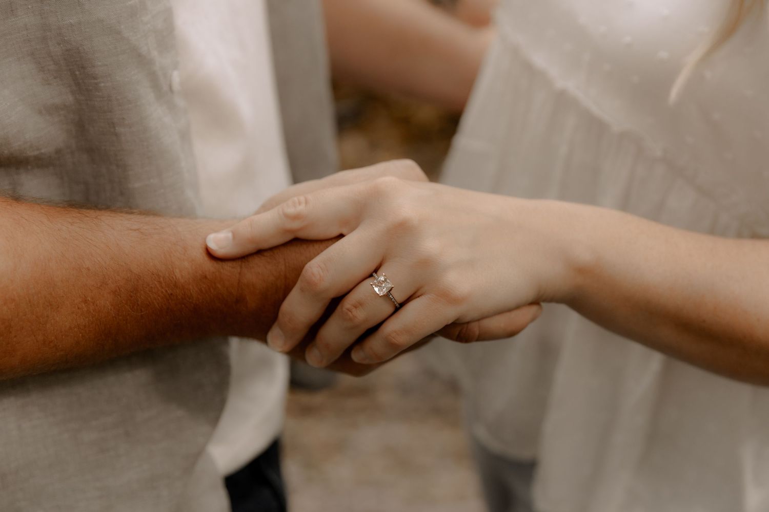 Close-up of hands with engagement ring showing a tender moment between a couple.