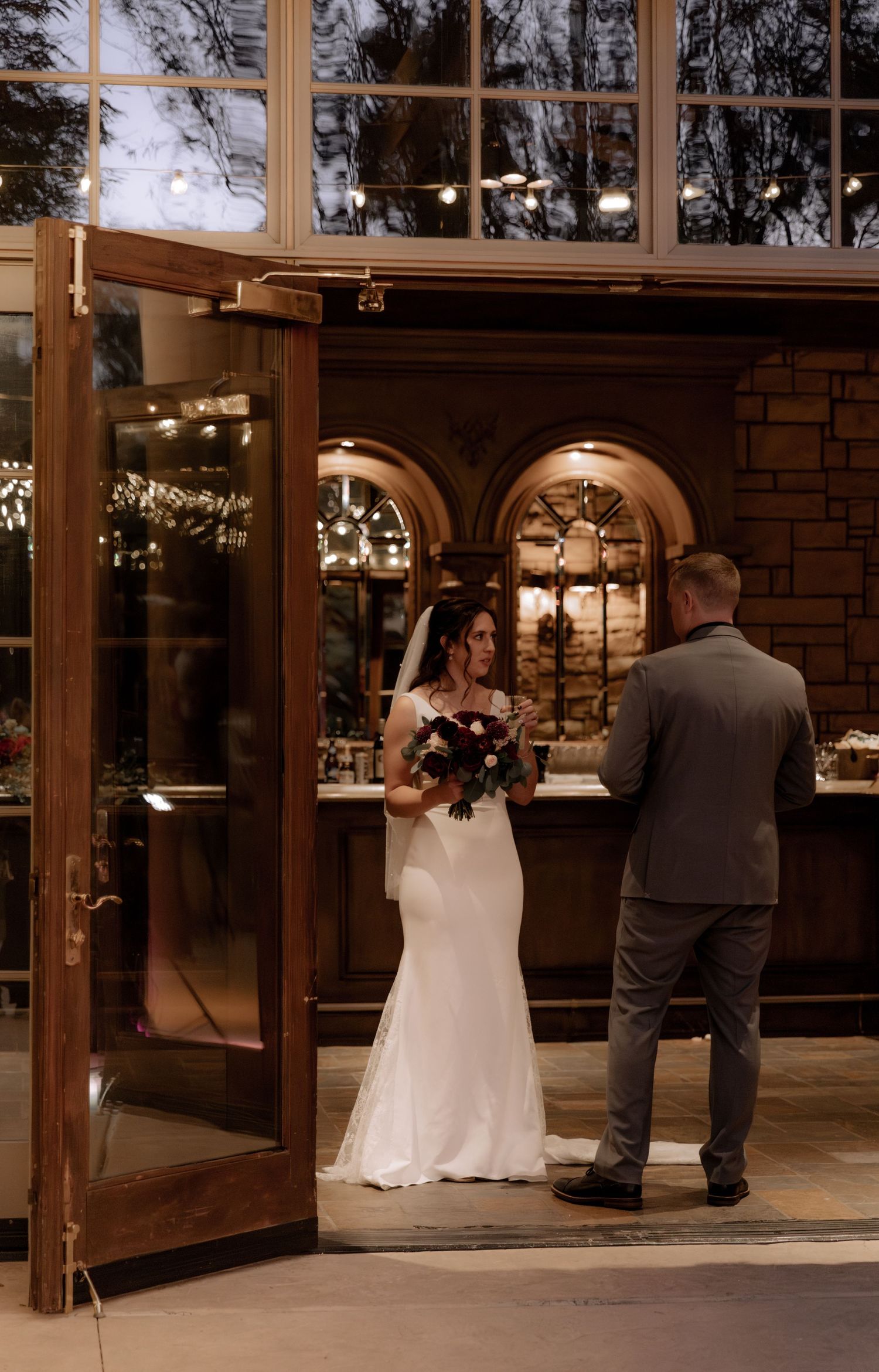Wedding scene at elegant venue with arched windows and romantic lighting.