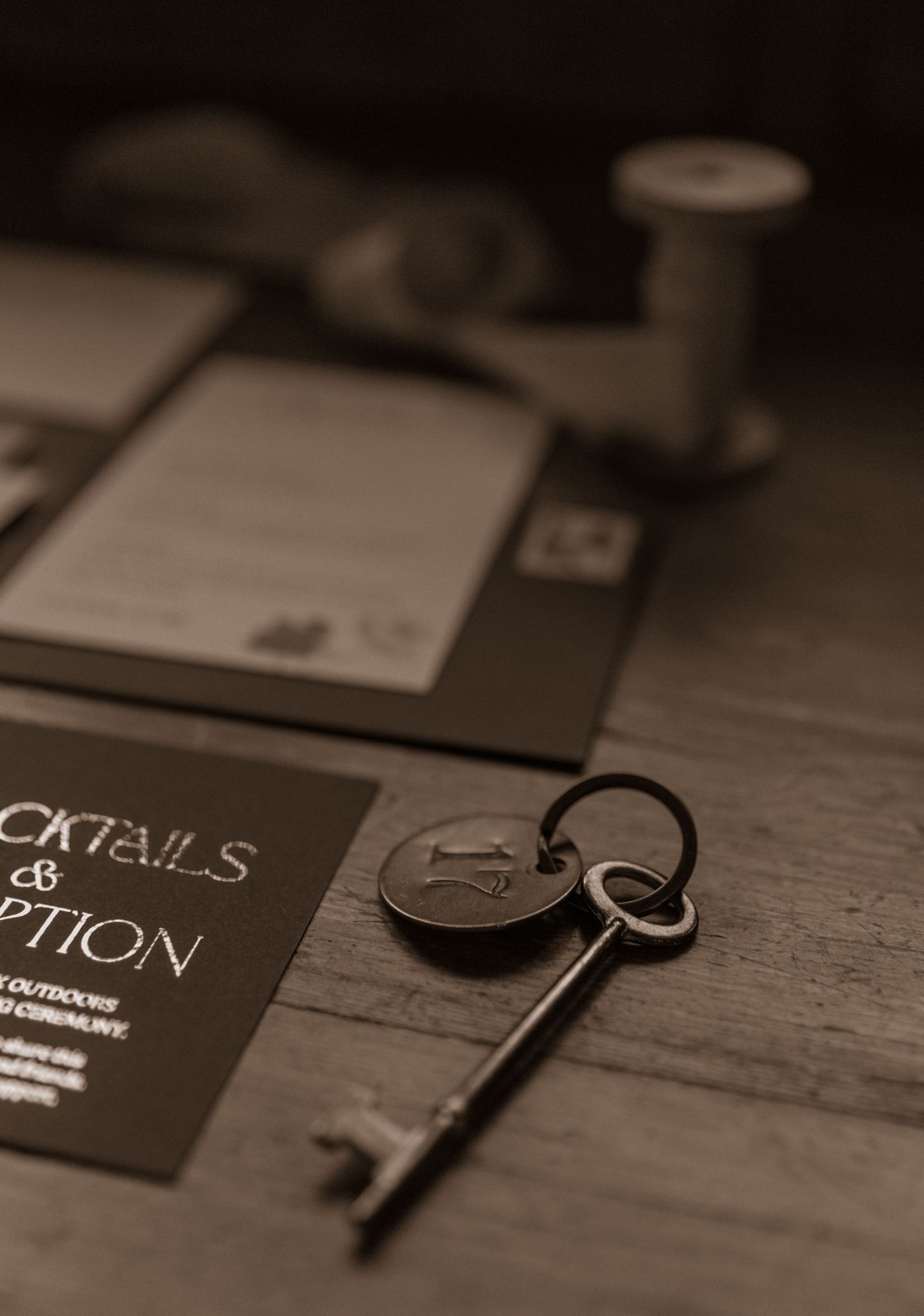 A vintage key and cocktail menu in moody lighting on a dark wooden surface.