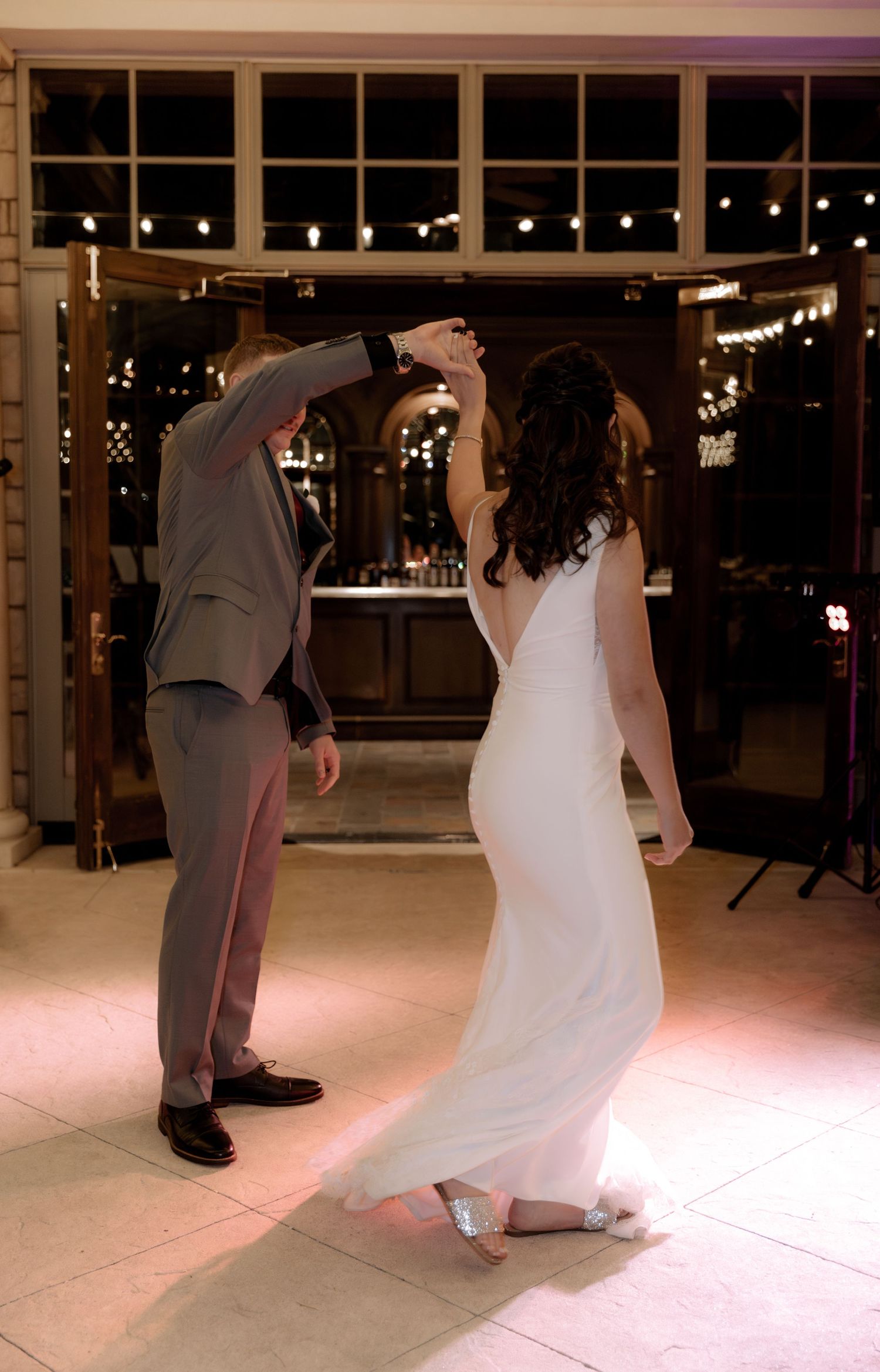 Couple performing a twirling dance move in an elegantly lit reception venue.