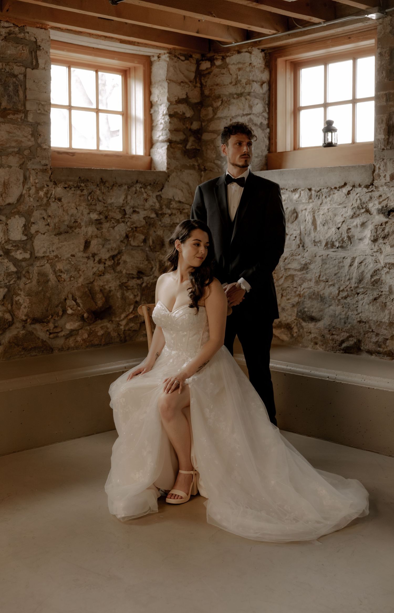 Elegant wedding portrait in a rustic stone room with wooden beam ceiling and natural light.