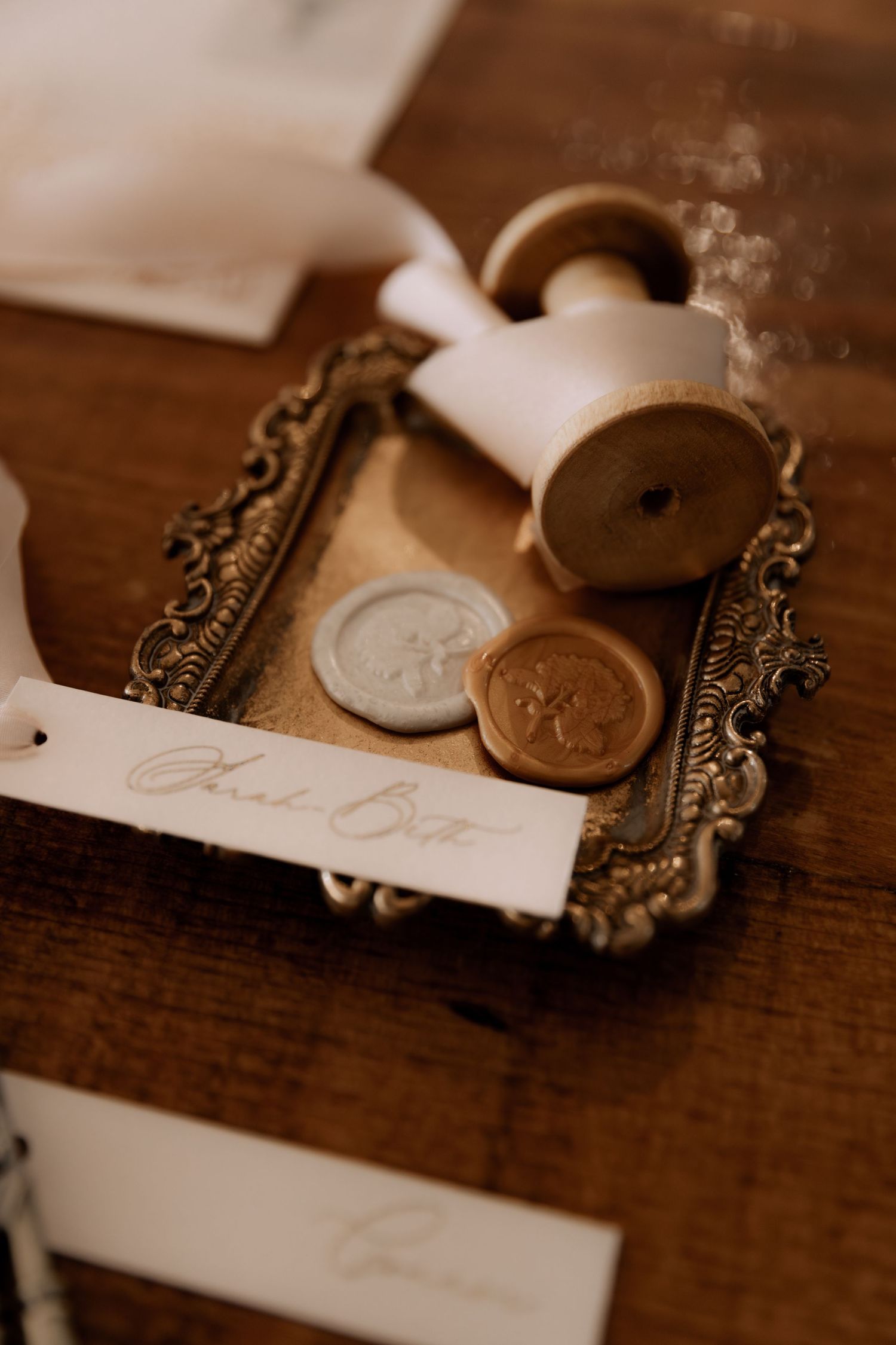 Vintage wax seal and coins displayed on an ornate antique frame on a wooden surface.