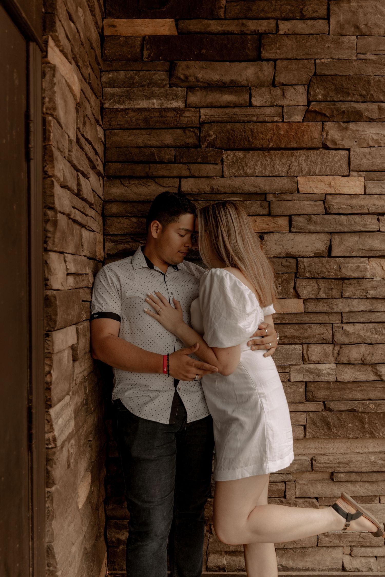 A romantic moment shared against a rustic stone wall background in warm lighting.