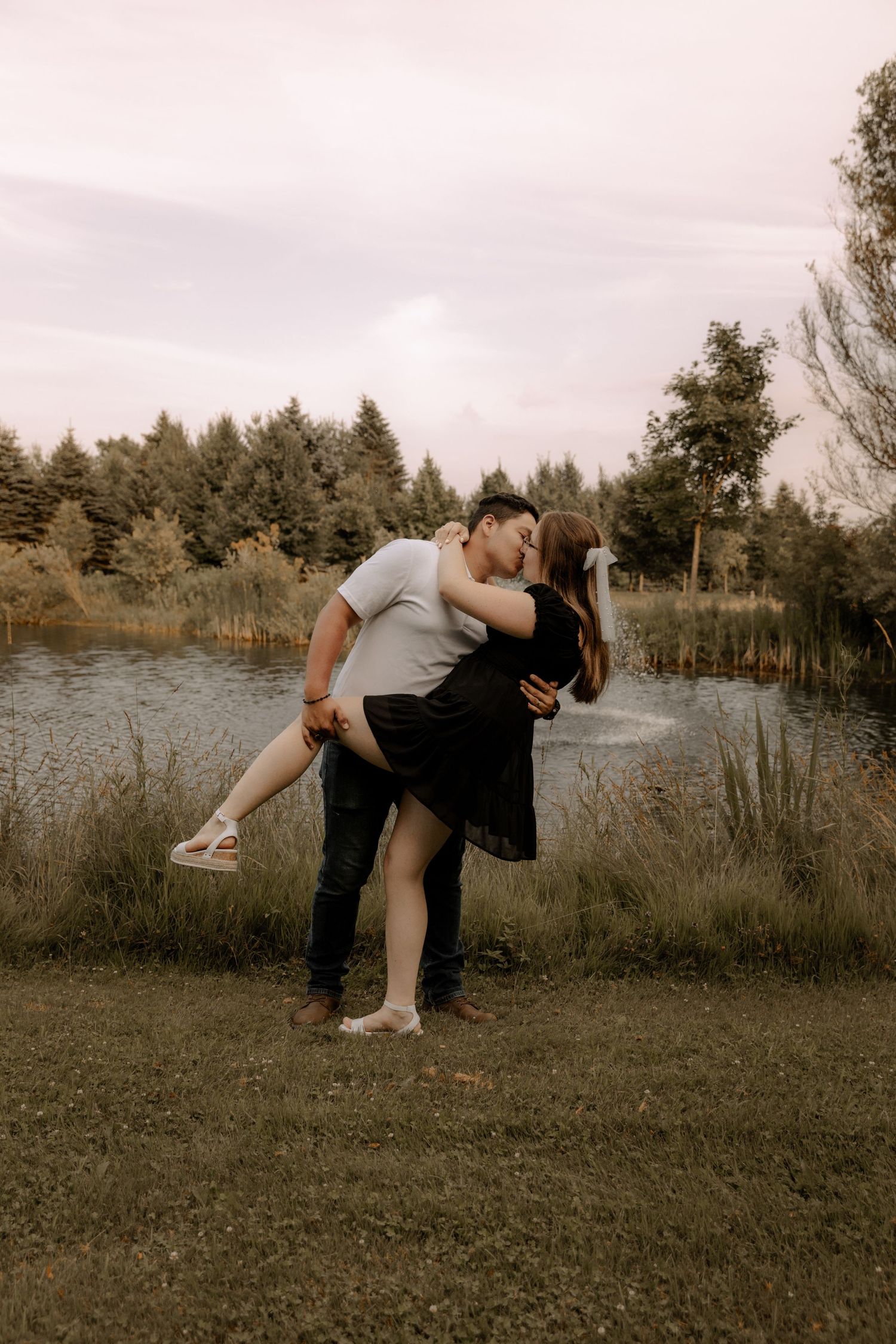A romantic dip pose against a backdrop of pine trees and marshland at sunset.