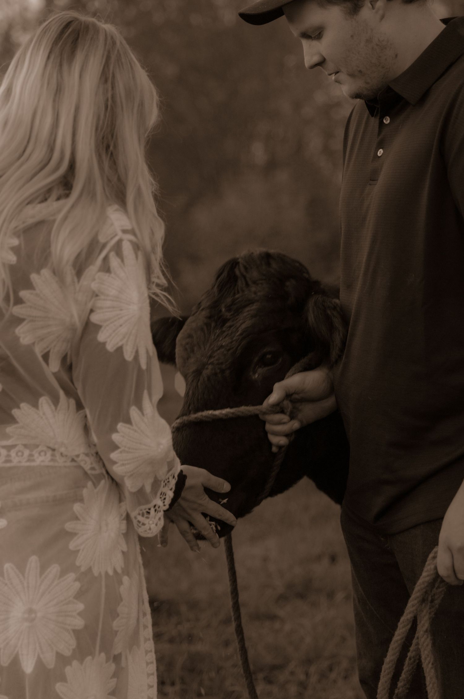Couple in rustic setting with a black dog on leash in sepia tones.