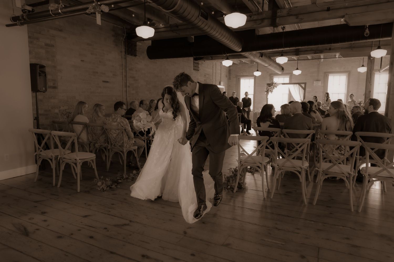 A joyful moment captured in sepia tones as a couple celebrates during their wedding ceremony.
