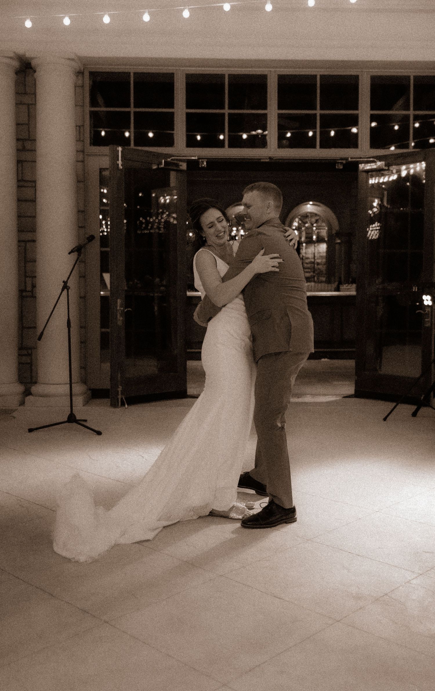 A romantic first dance moment between newlyweds in an elegantly lit venue.