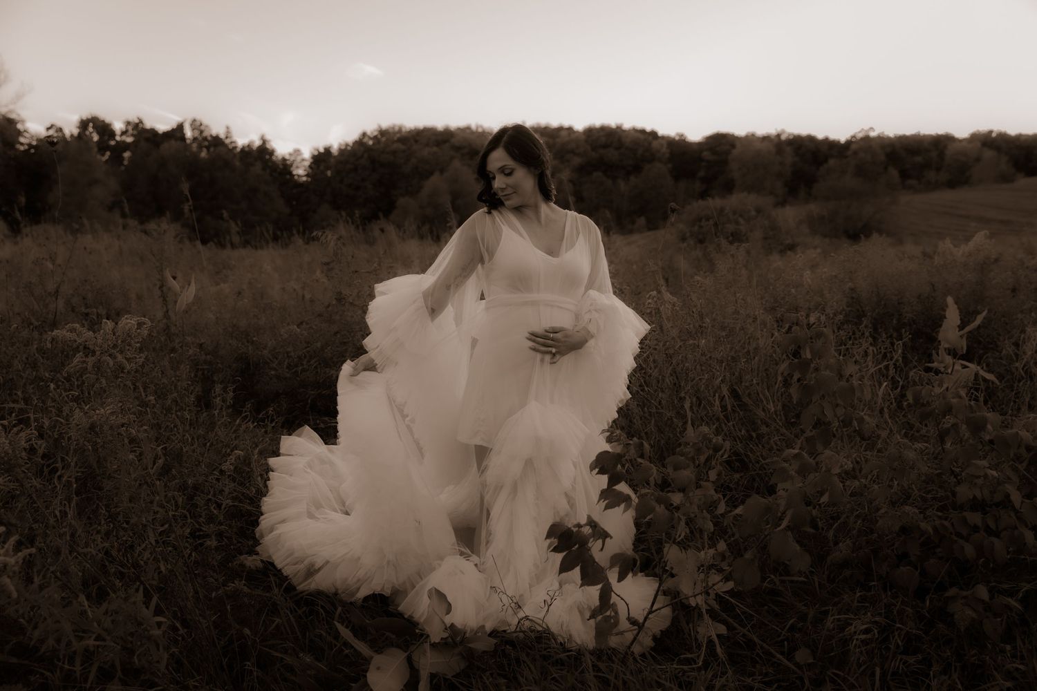 Artistic black and white capture of flowing wedding dress in natural field setting.