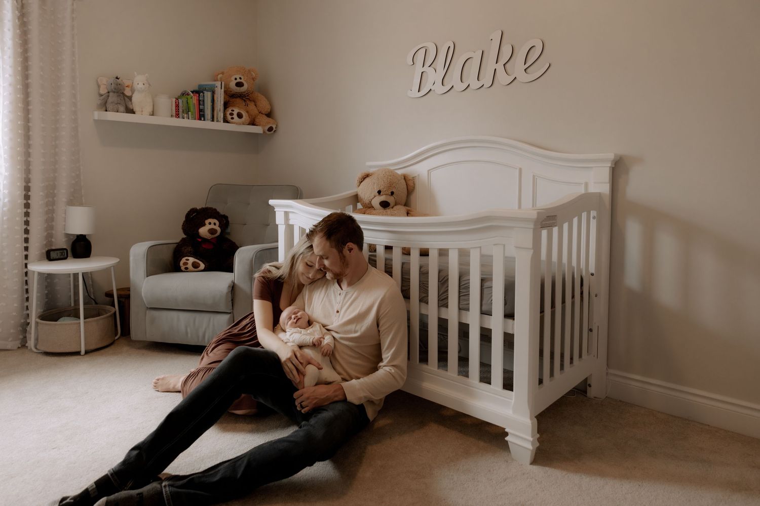 A quiet nursery moment in front of a white crib with a decorative name displayed on the wall.