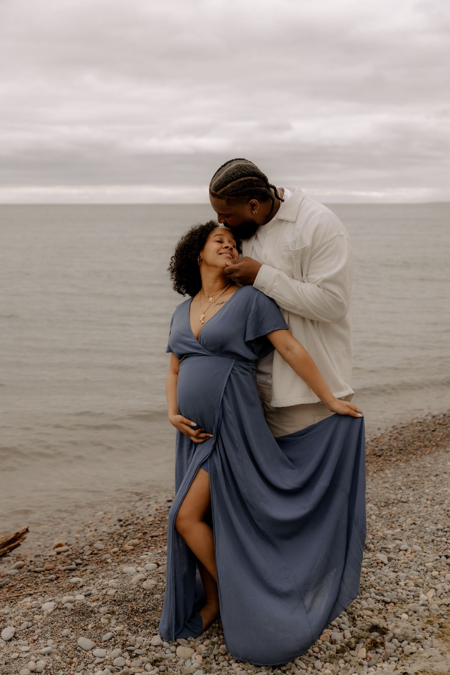 A maternity photo showing a tender embrace on a rocky beach.