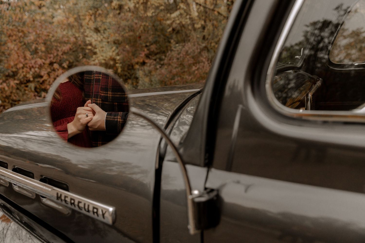 A classic Mercury truck's side mirror captures a romantic autumn scene.