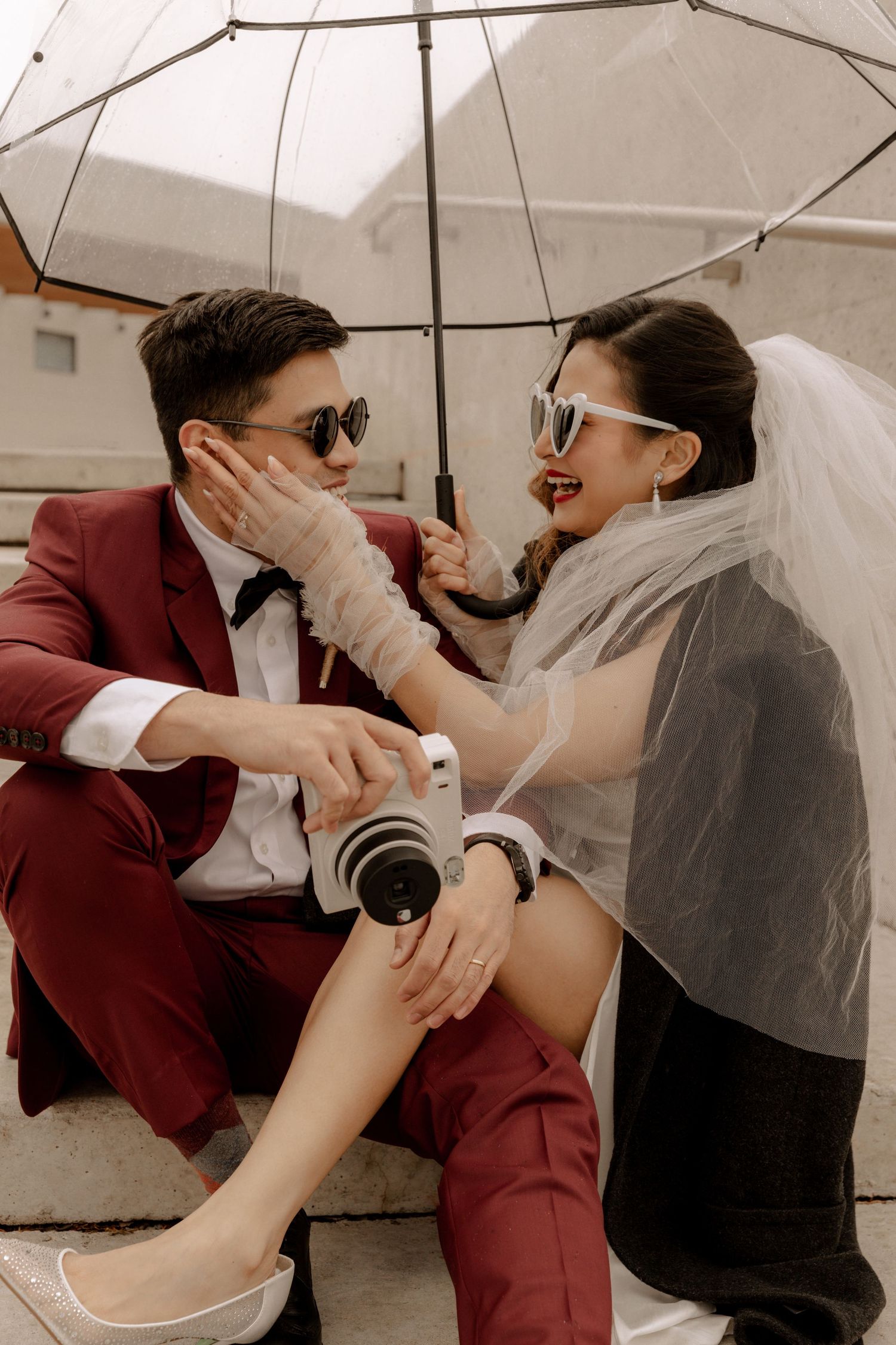 Intimate wedding moment under white umbrella with vintage camera.
