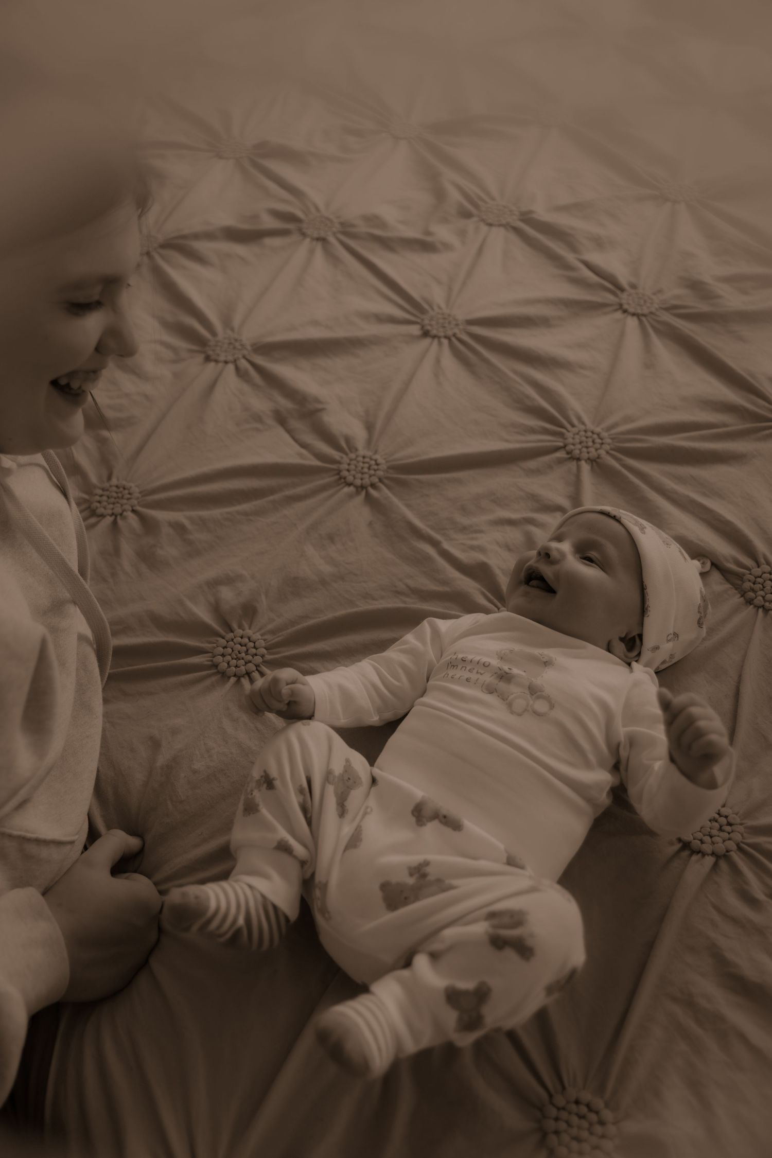 A tender moment of bonding shown in sepia tones against a tufted fabric backdrop.