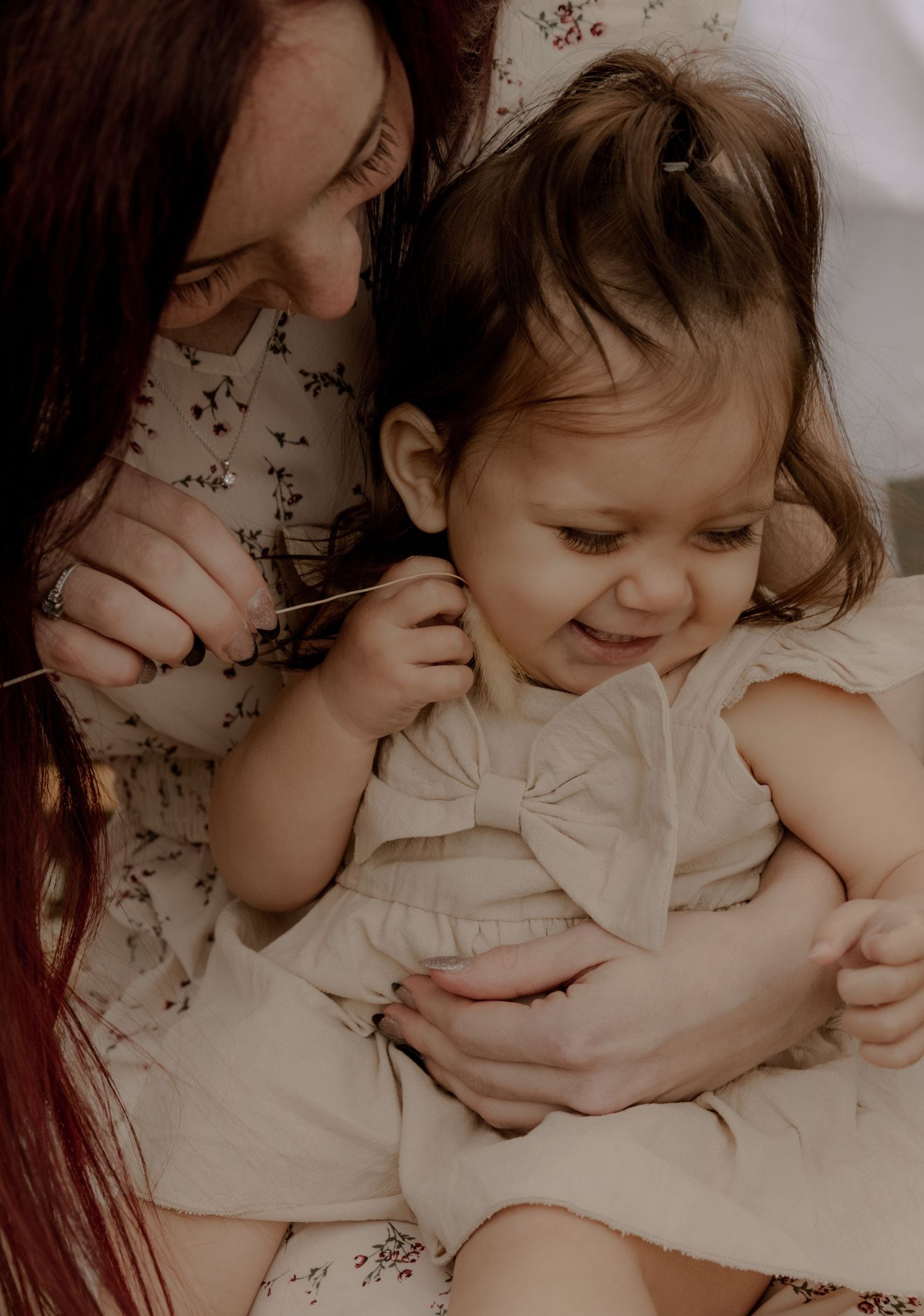 Sweet candid moment of shared laughter and play against a floral patterned background.