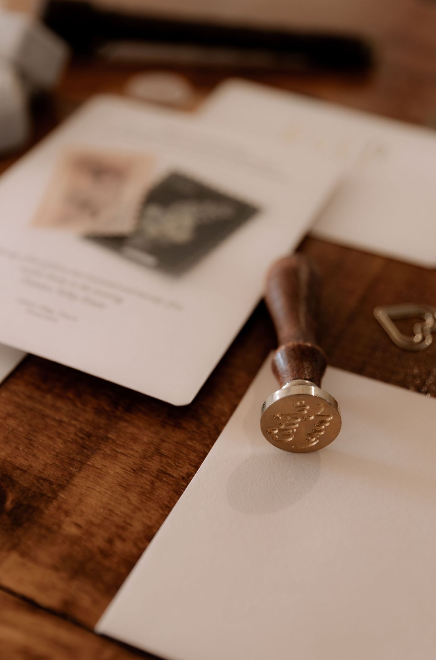 Vintage wax seal and wedding stationery displayed on wooden surface.