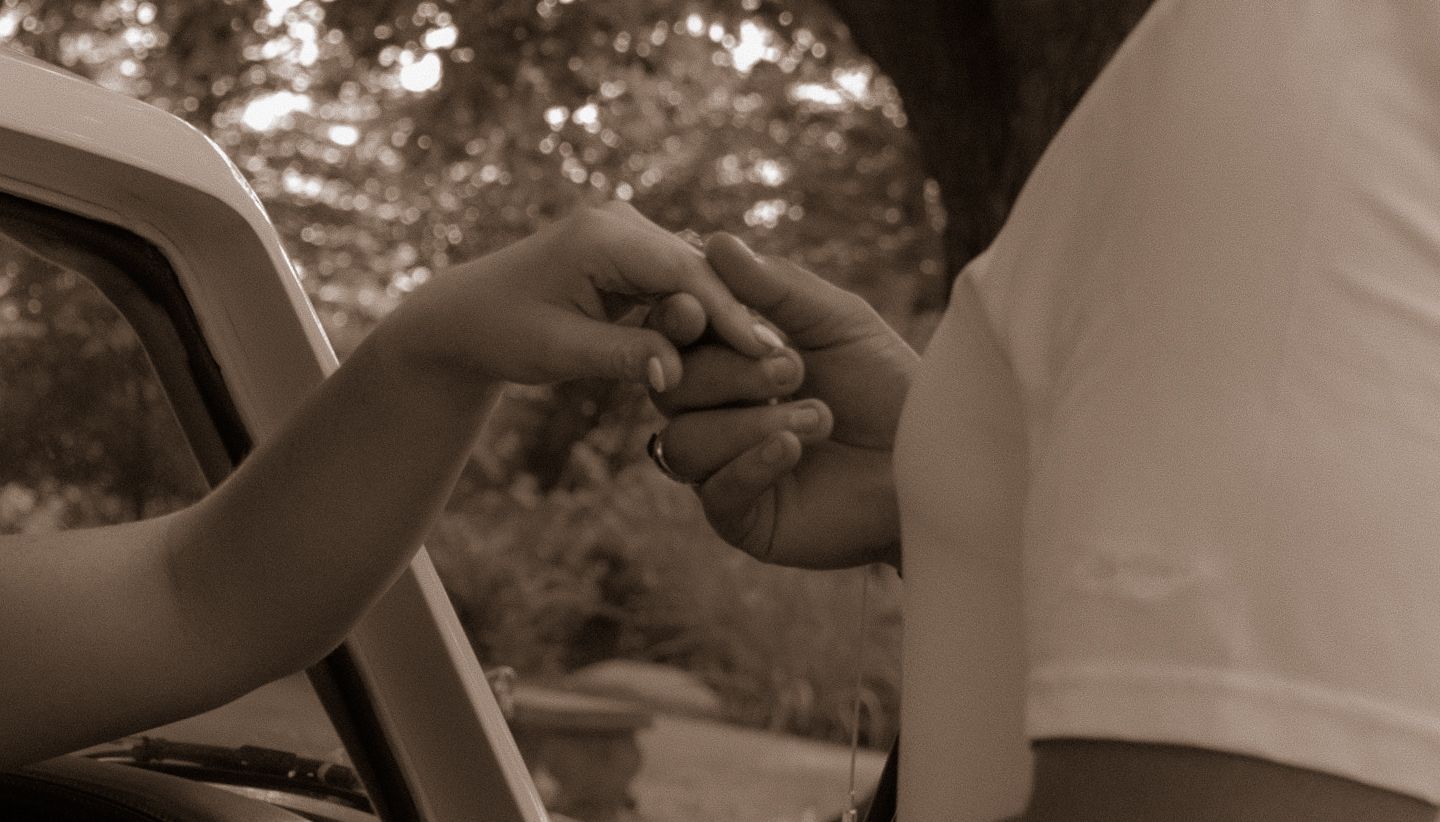 A close-up black and white shot of two hands reaching toward each other.