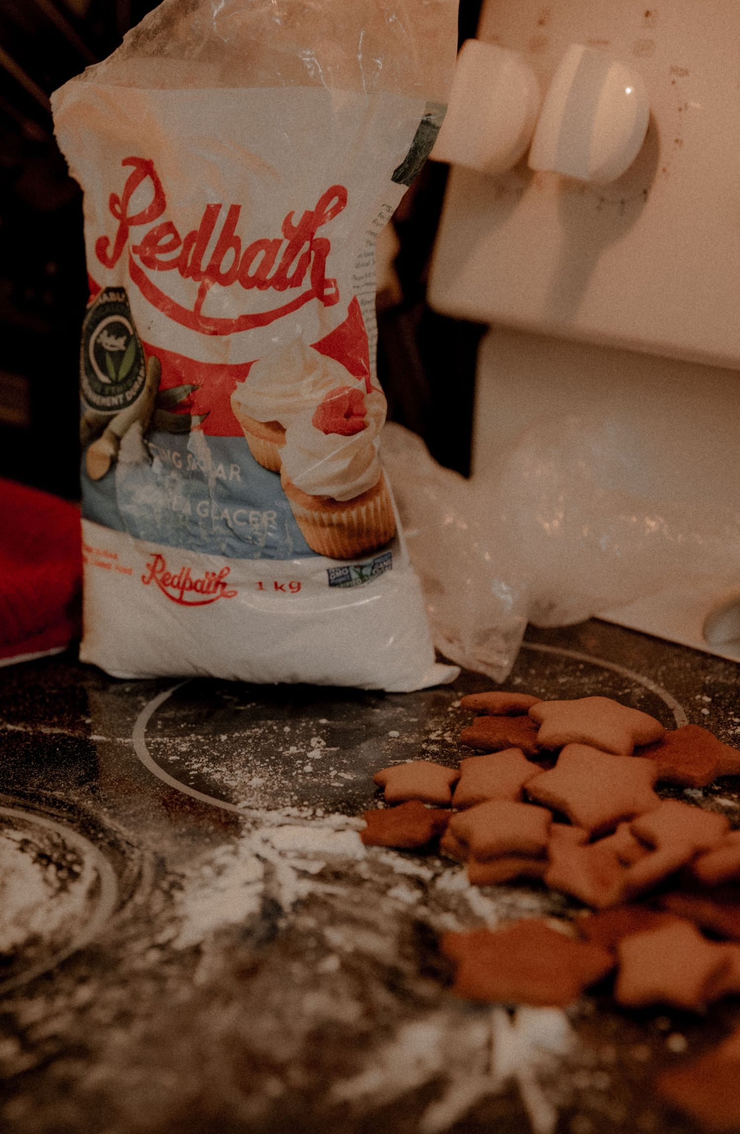 A bag of Redpath sugar and gingerbread cookies on a flour-dusted counter.