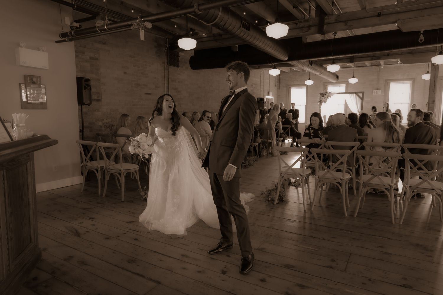 A vintage-style wedding photograph showing movement and joy in an industrial chic setting.