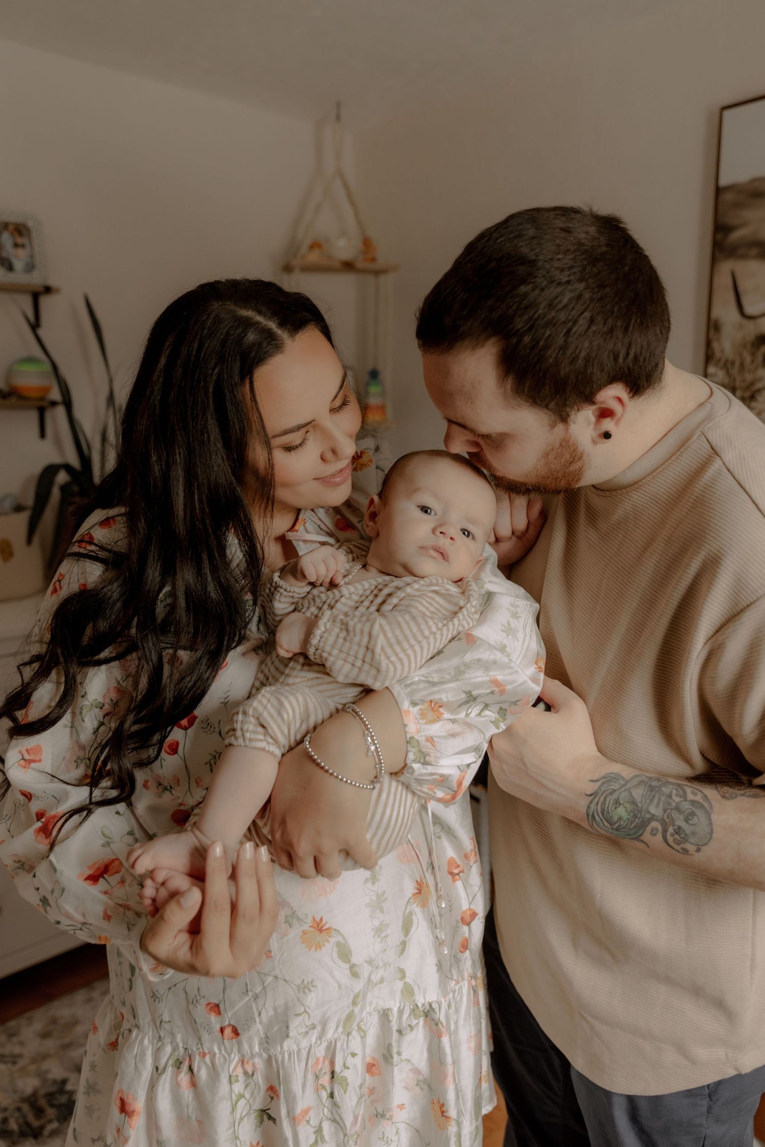 A tender moment between parents and their baby captured in warm tones, showing gentle affection and love.