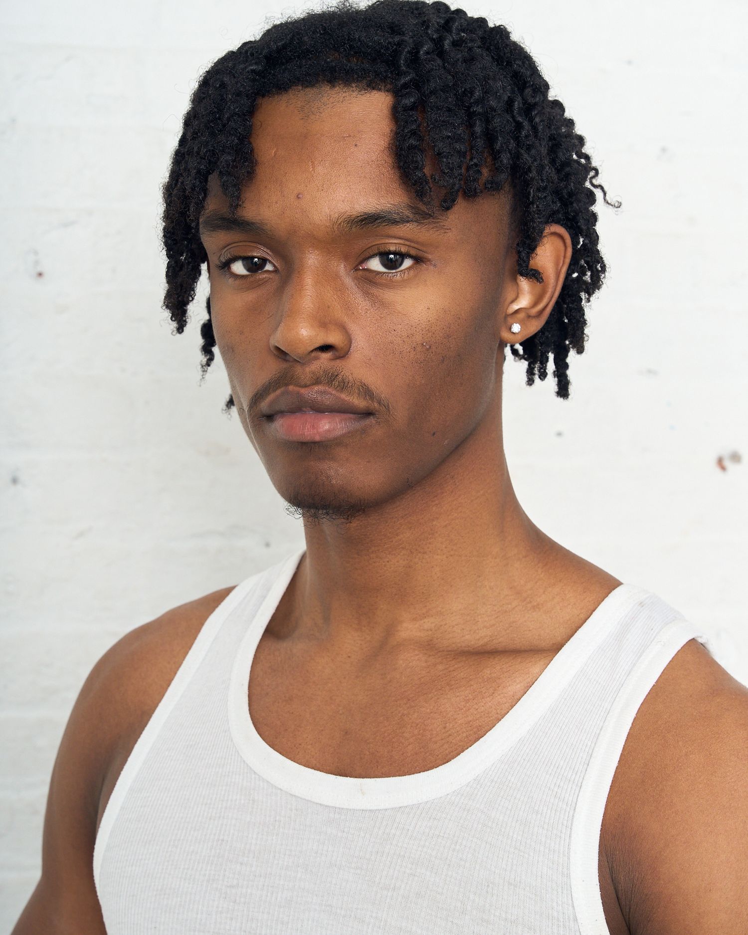 Model in white tank top poses for headshot against white background. Modeling Digitals