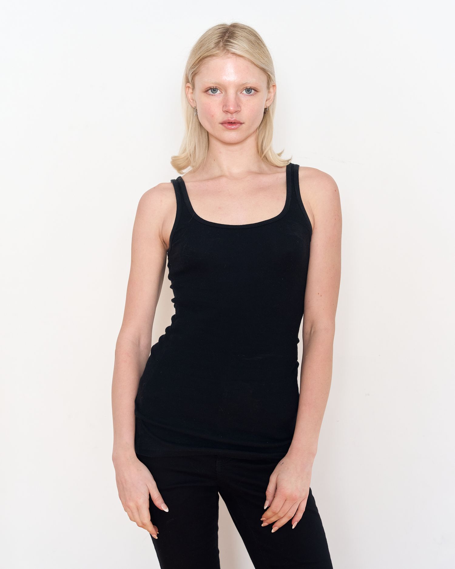 Model in fitted black tank top poses against white studio backdrop. Modeling Digitals
