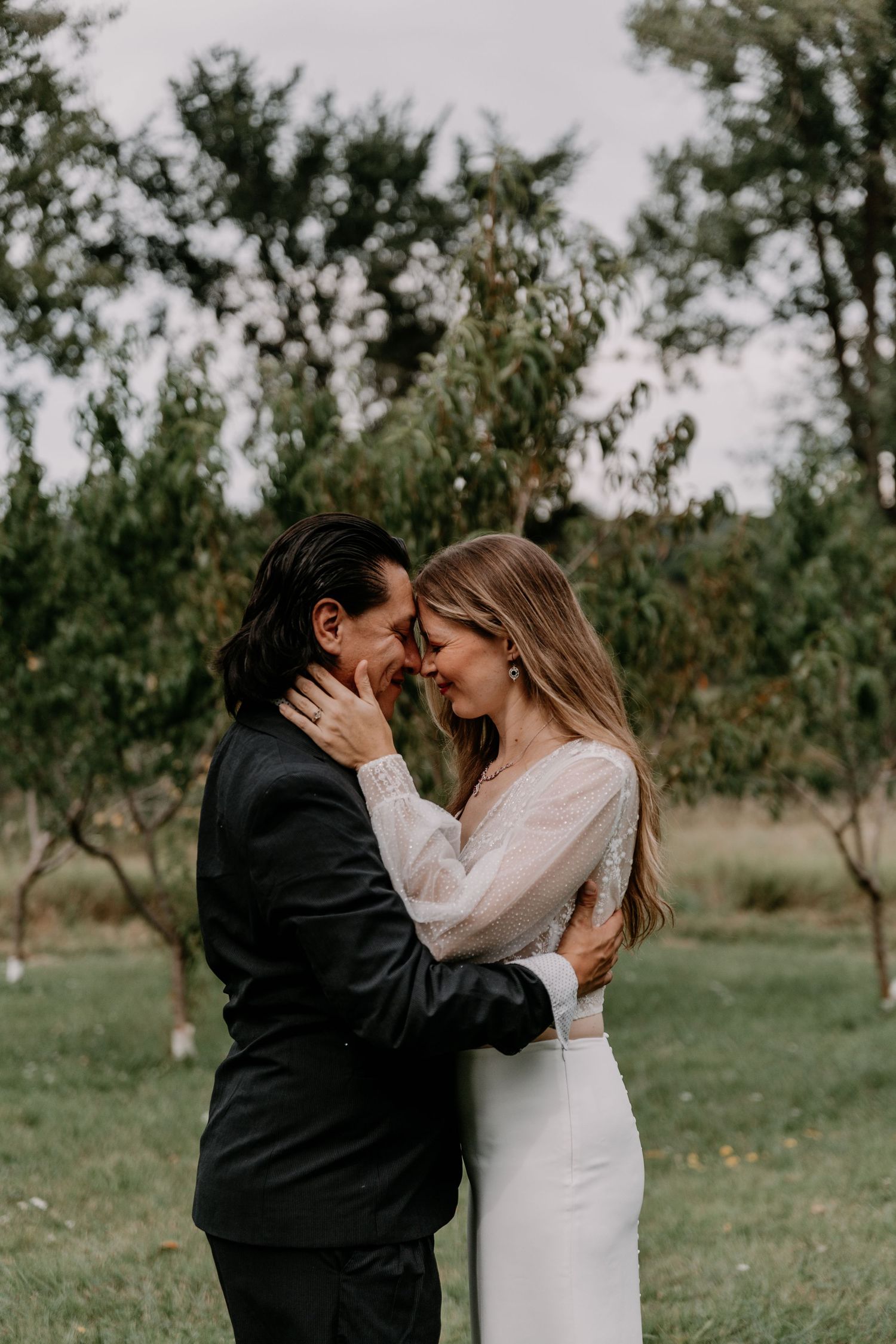 Romantic embrace between newlyweds in garden setting with natural lighting.