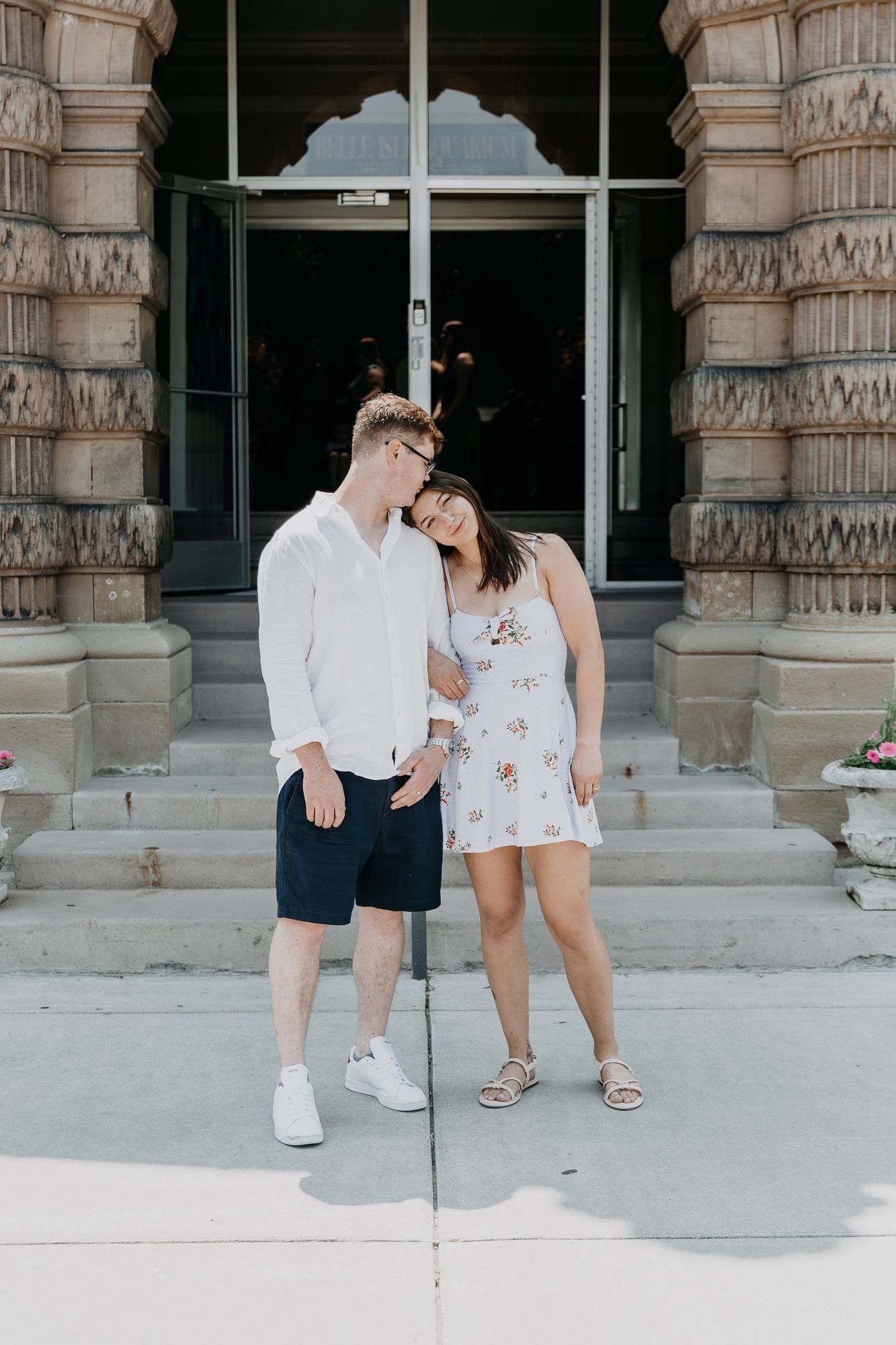A couple shares playful moments on stone steps outside a building.