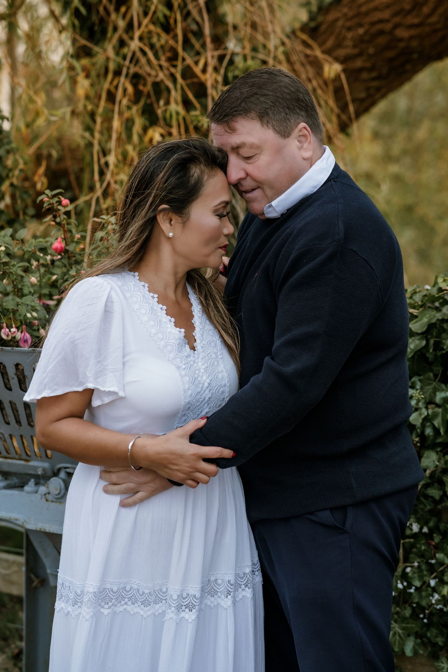 Intimate moment between couple in formal attire standing in garden setting.