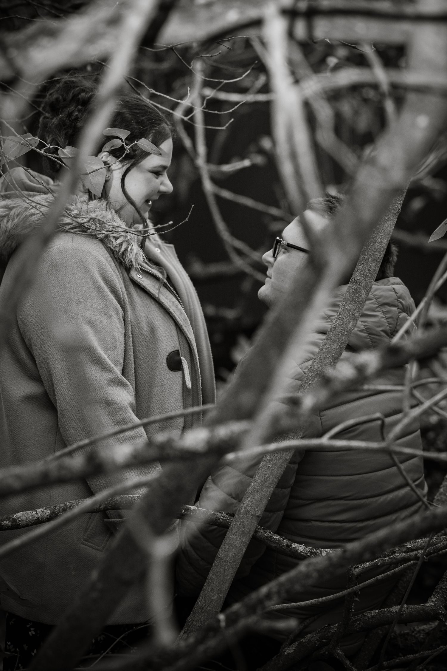 Artistic black and white portraits taken through tree branches creating natural framing.
