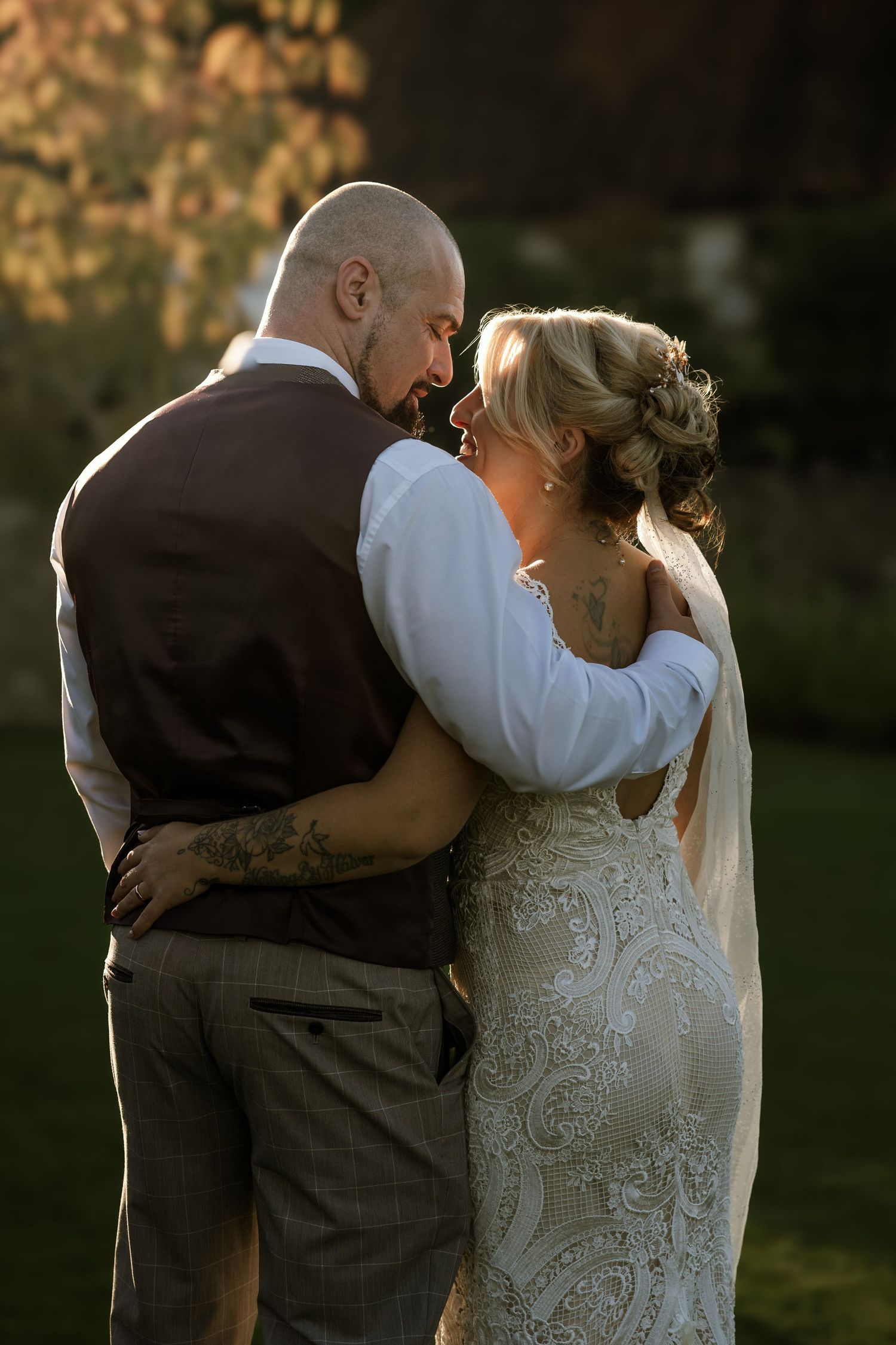 A romantic wedding portrait showing a couple embracing during golden hour in their wedding attire.