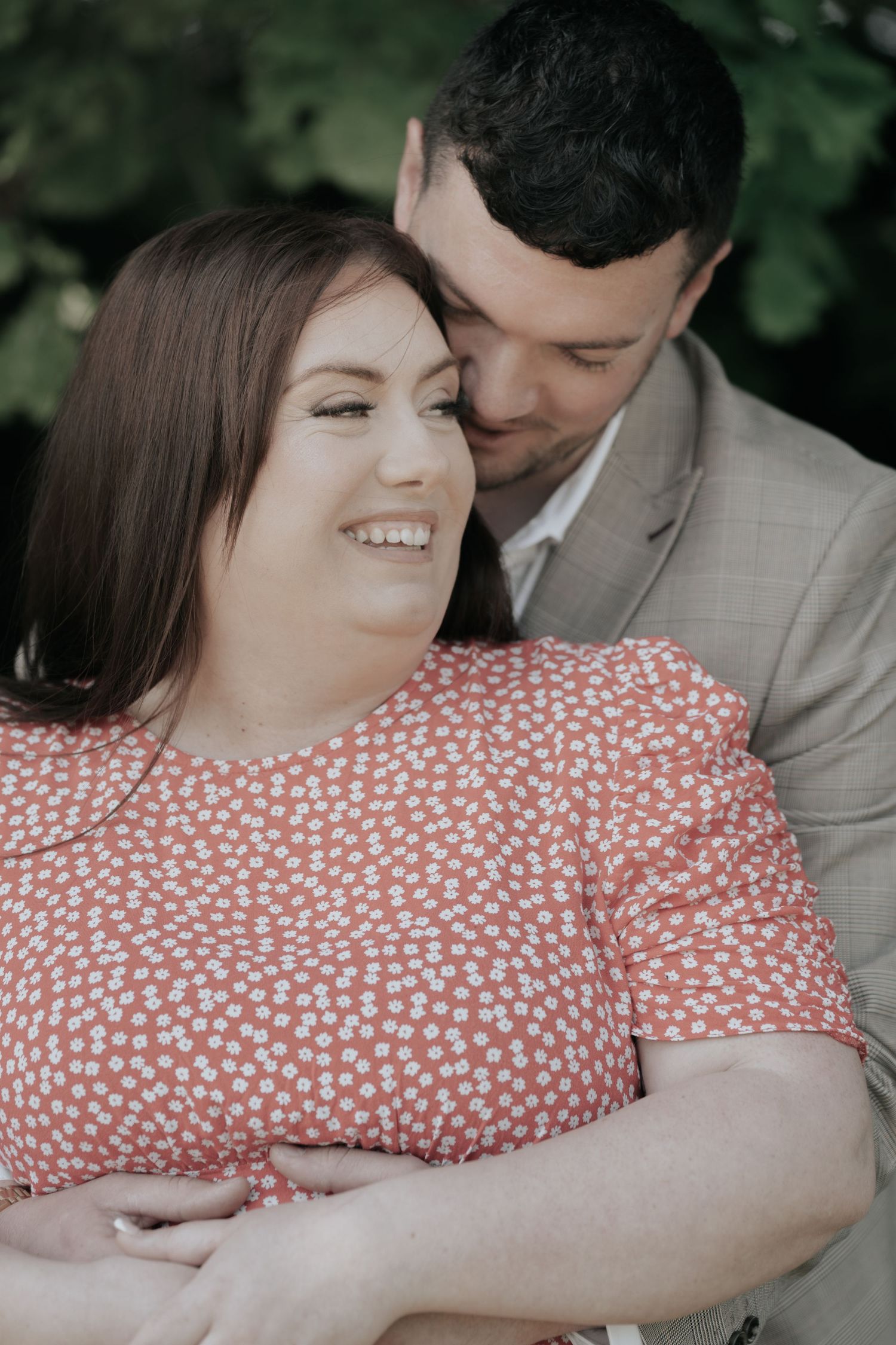 A tender close-up portrait of a couple embracing while wearing coordinating pink and grey outfits.