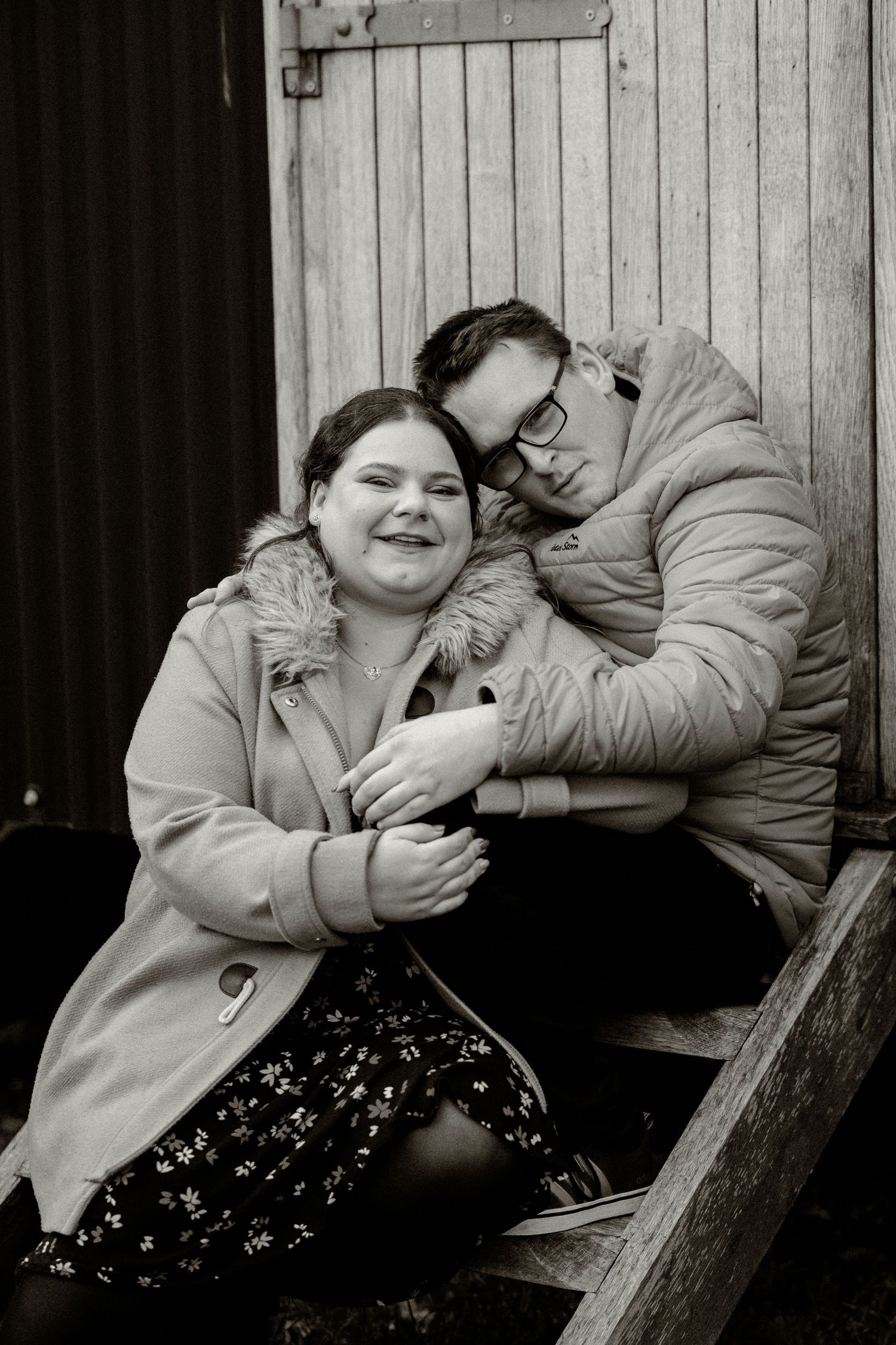 Black and white portrait series showing intimate moments against a wooden wall background.