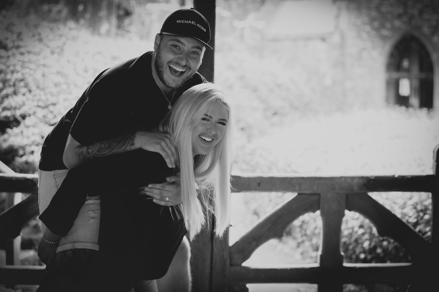 A playful black and white portrait of a couple sharing laughter outdoors.