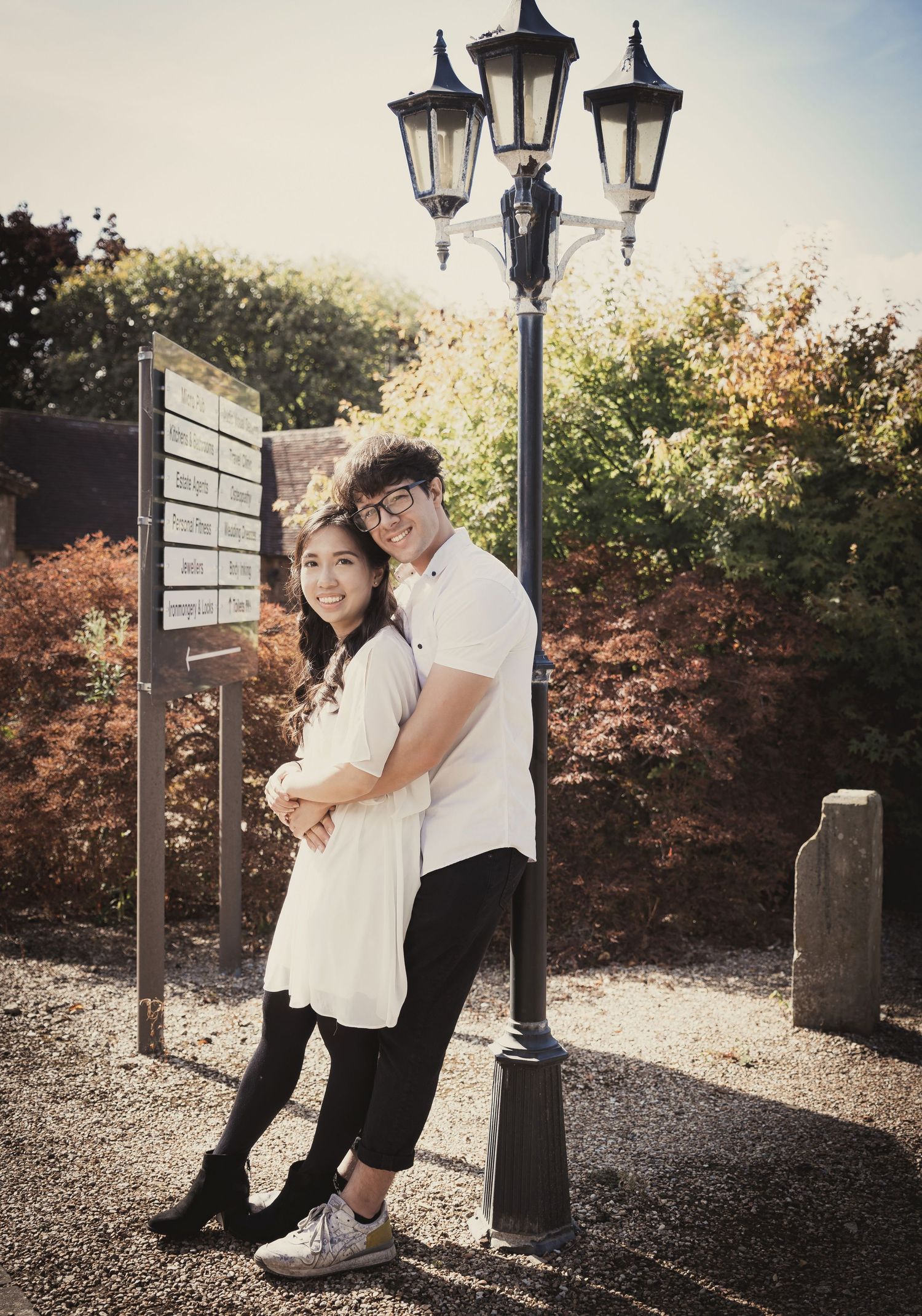A couple poses playfully by a vintage street lamp post.