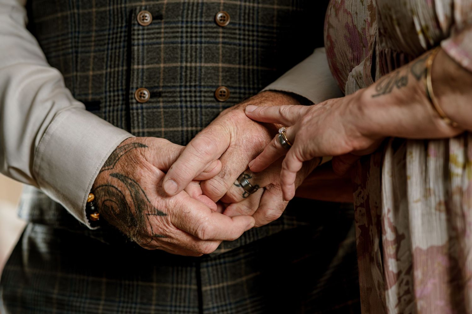 Close-up view of elderly hands covered in paint stains exchanging something while wearing formal clothing.