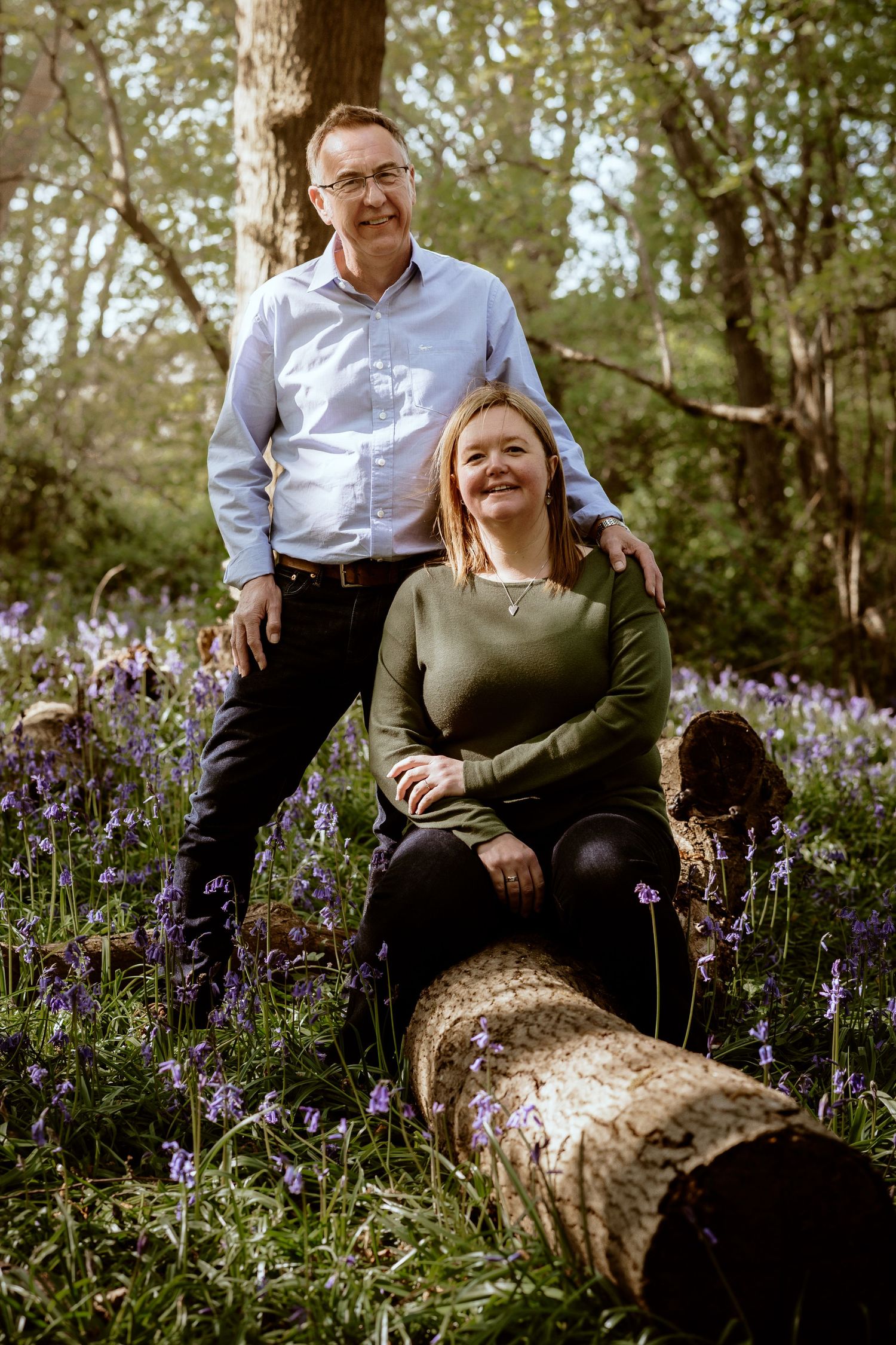 Casual engagement portrait in a blooming bluebell woodland setting.