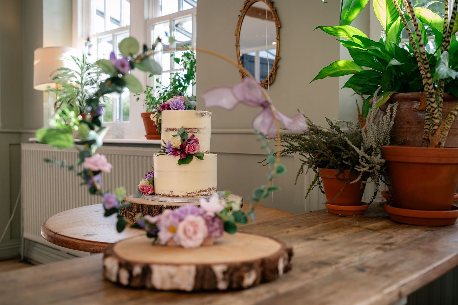 Decorative wedding table setting with wooden slice centerpiece and potted plants.