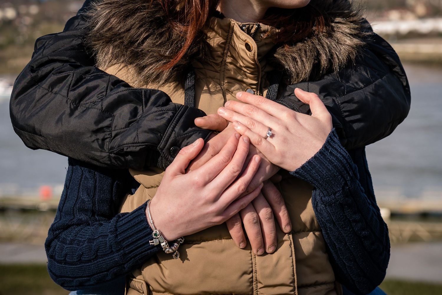 Close-up shot of couple embracing outdoors in casual winter attire.