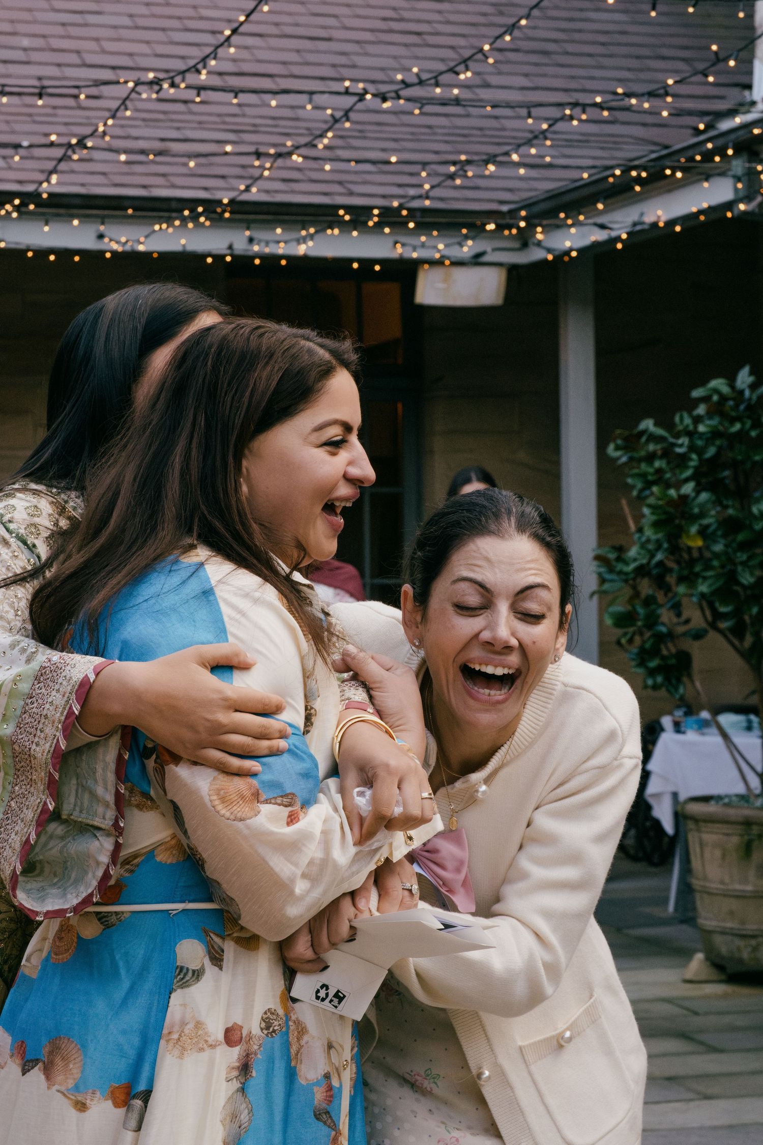 A series of candid moments showing two friends in blue and cream colored outfits embracing and laughing together.