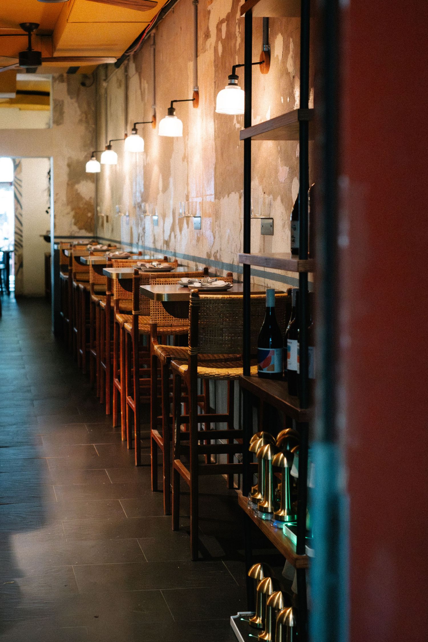 Modern restaurant interior with rows of wooden tables and pendant lights creating an inviting dining atmosphere.