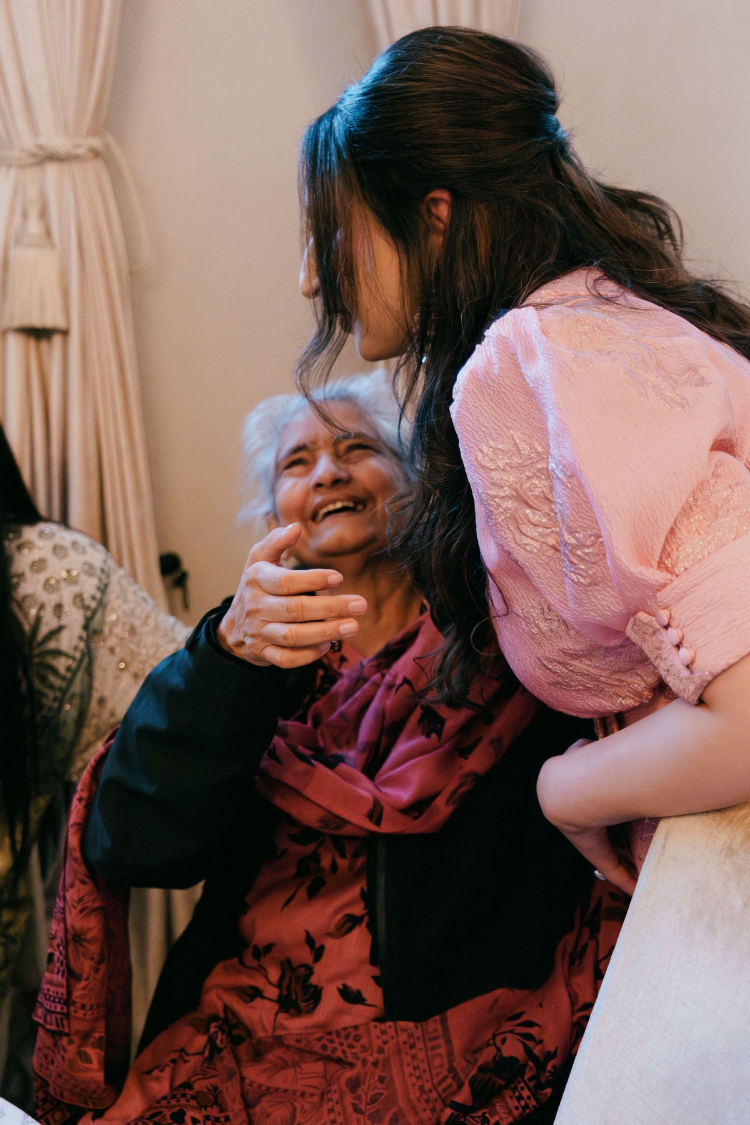 A tender moment shared between two people, one wearing pink and another in dark clothing with a floral pattern.