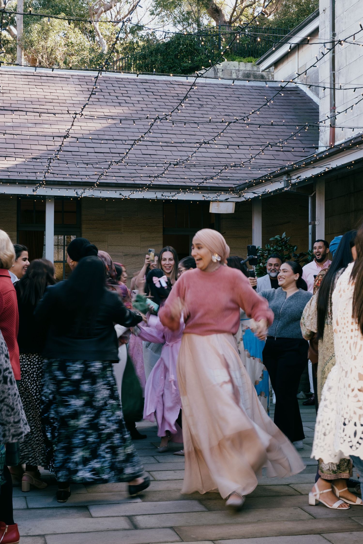 A group of people dancing and socializing on an outdoor covered deck under a wood-shingled roof.