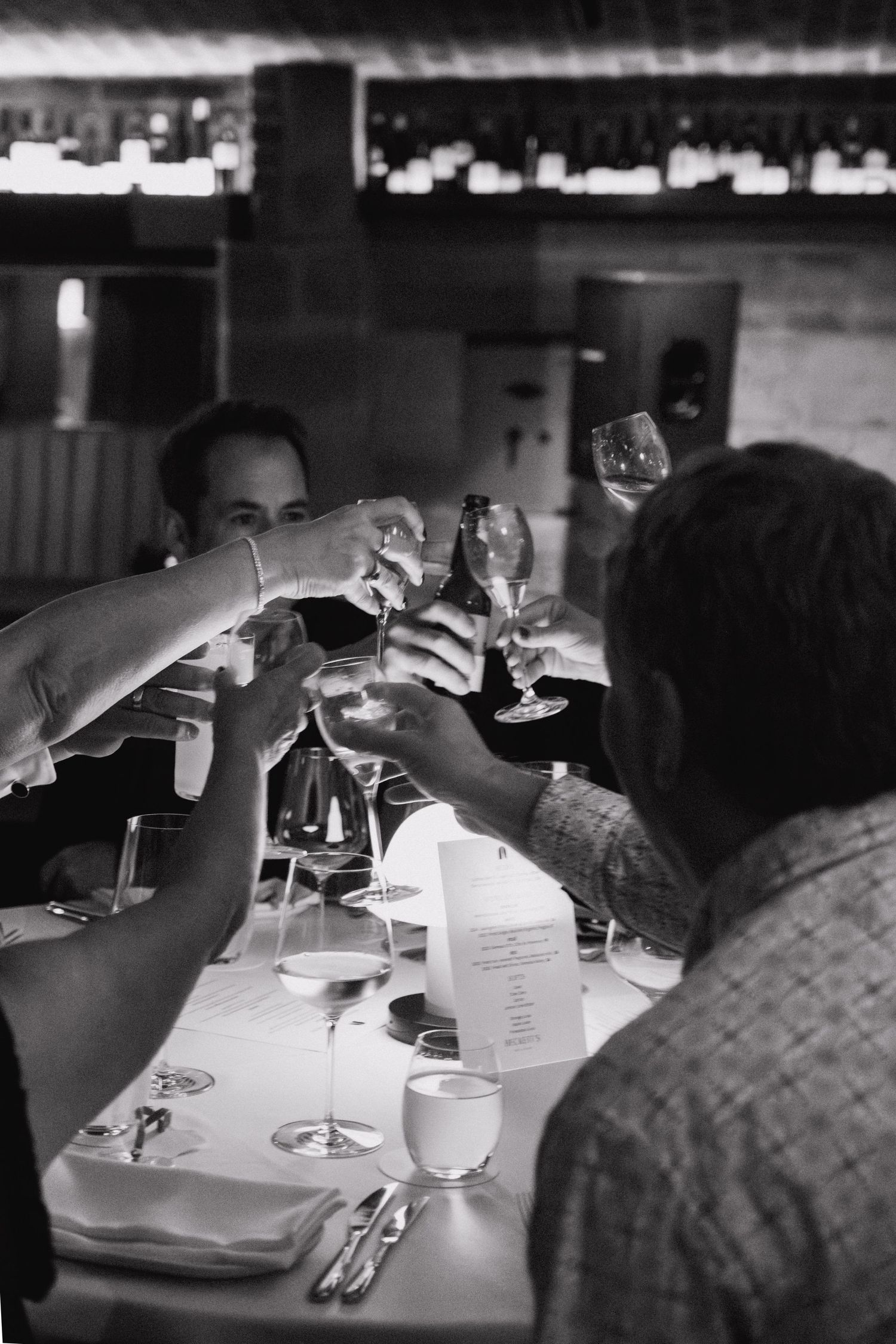 Black and white photo series showing wine glasses on a white tablecloth during a restaurant dining experience.
