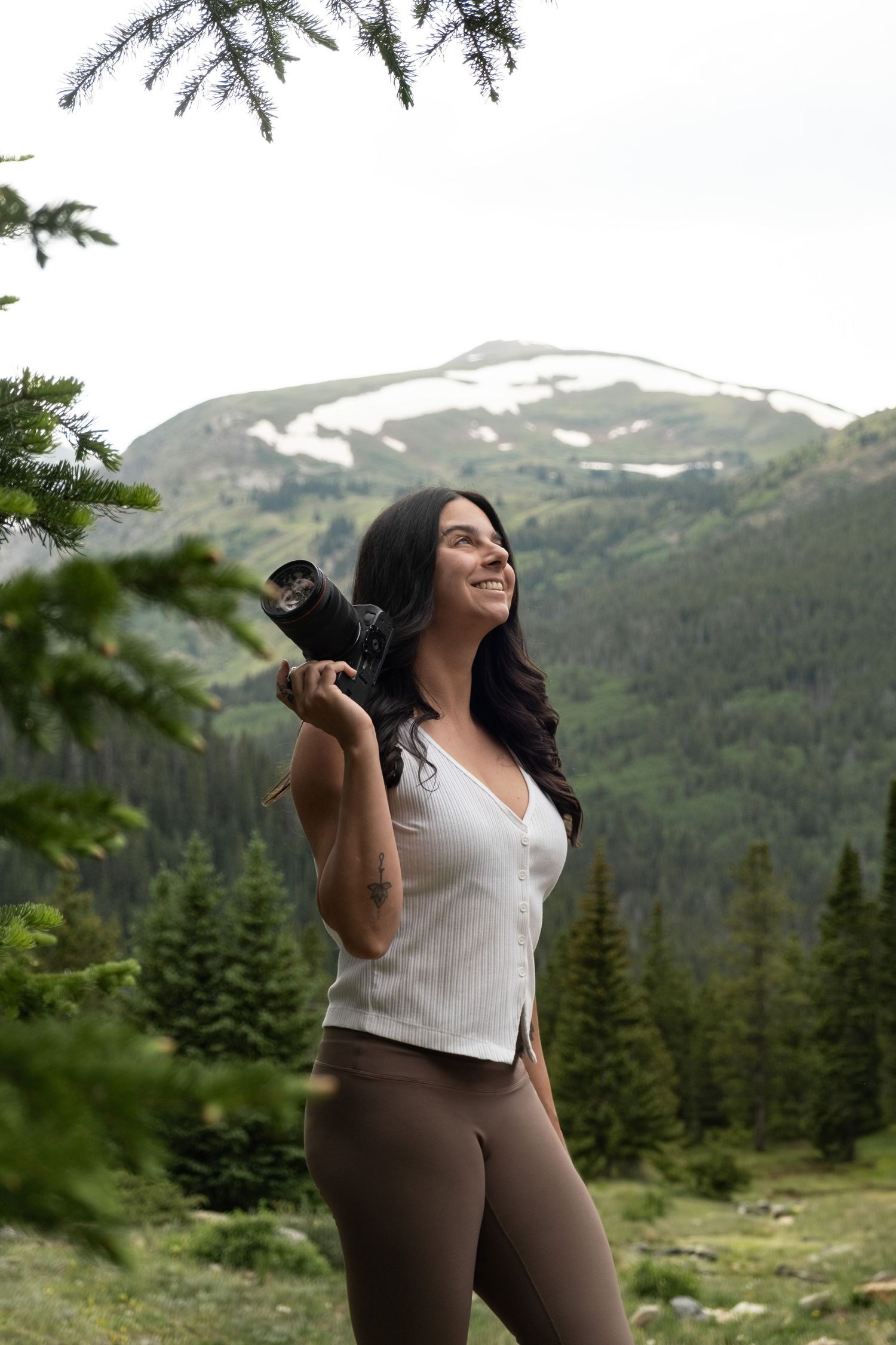 A Breckenridge photographer takes photos in a scenic mountain landscape with snow-capped peaks.